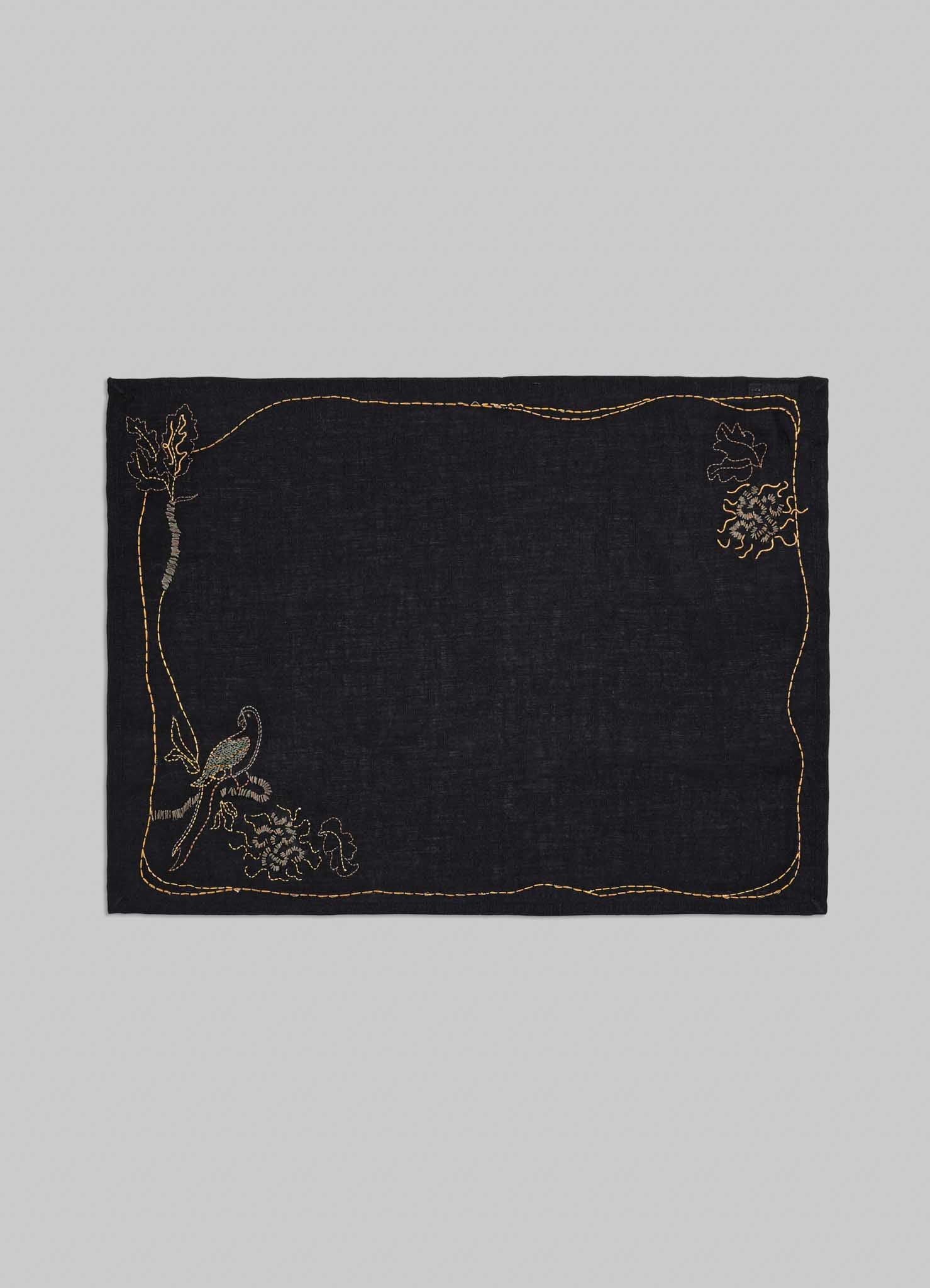 Black fabric square with gold embroidery on a gray background viya luxury placemats