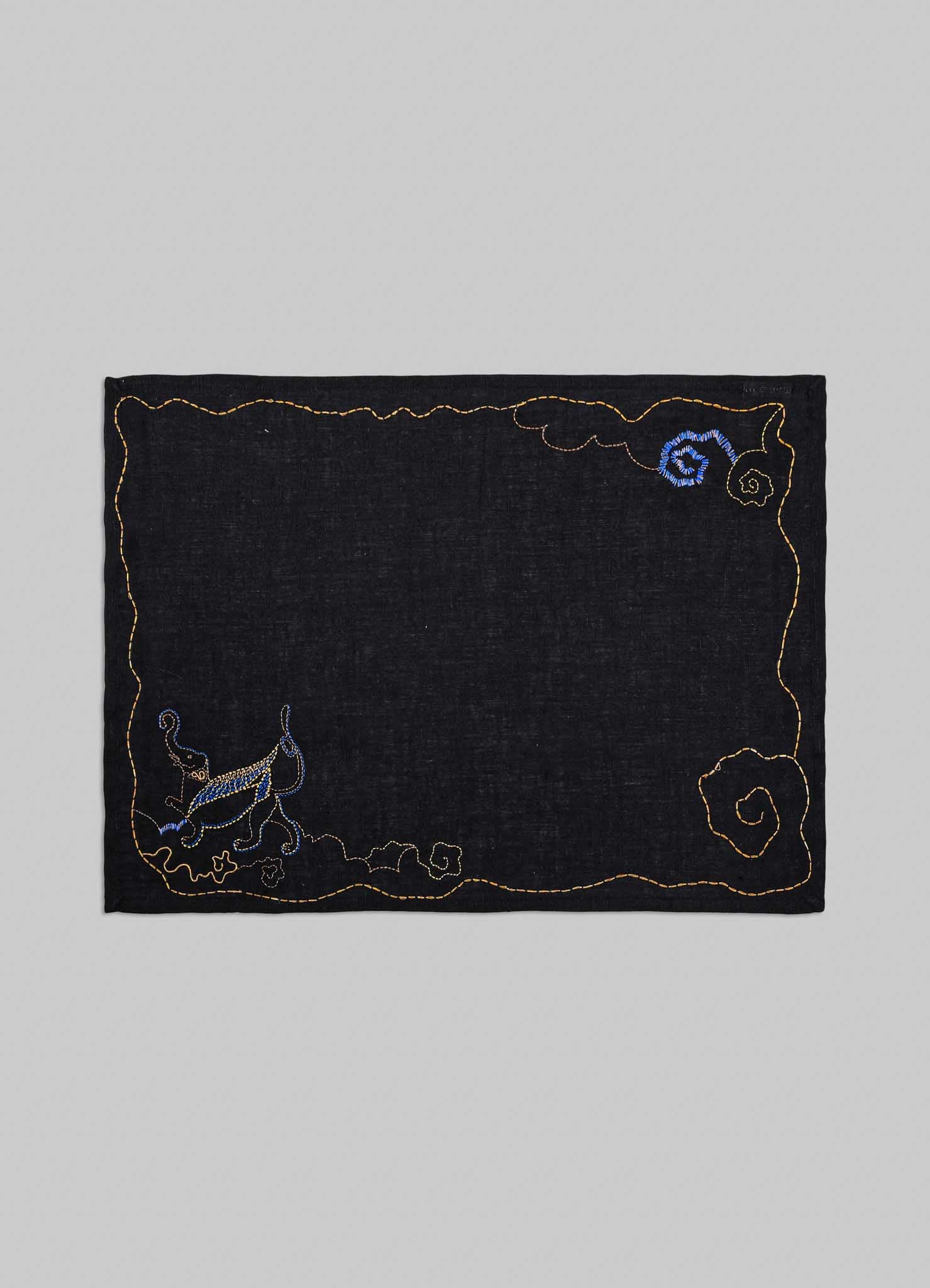 Embroidered black fabric patch with decorative elements on a gray background viya luxury placemats