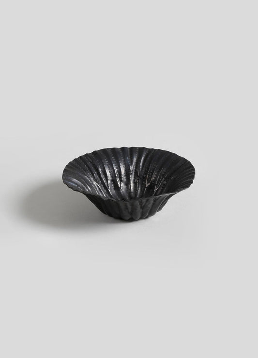 A black scalloped dish or bowl with a glossy finish, featuring a ridged, fan-like pattern on the surface.