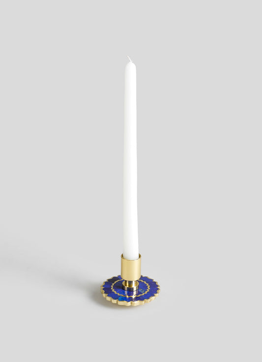 A candlestick holder made of metal with a gold finish and a decorative blue and gold scalloped base, designed to hold a tall, white taper candle.
