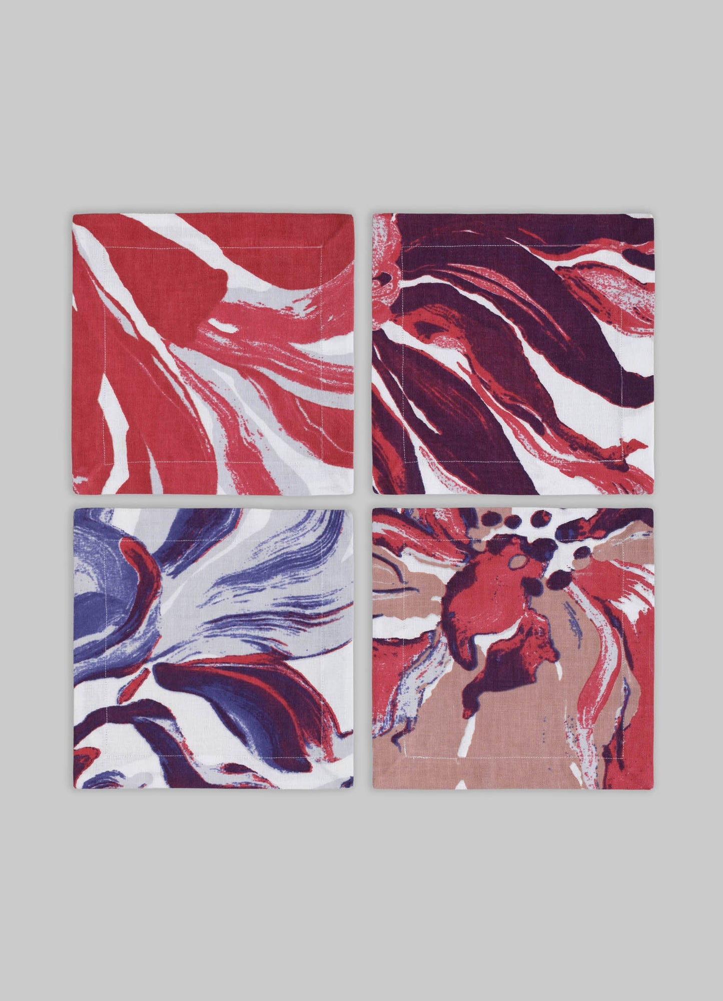 Set of four fabric napkins with bold abstract floral motifs in red, purple, blue, and beige tones, featuring fluid brushstroke patterns on a white background.