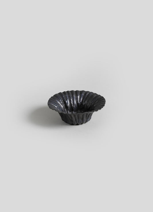 Black ceramic scalloped bowl with a glossy finish and a ridged, textured surface.