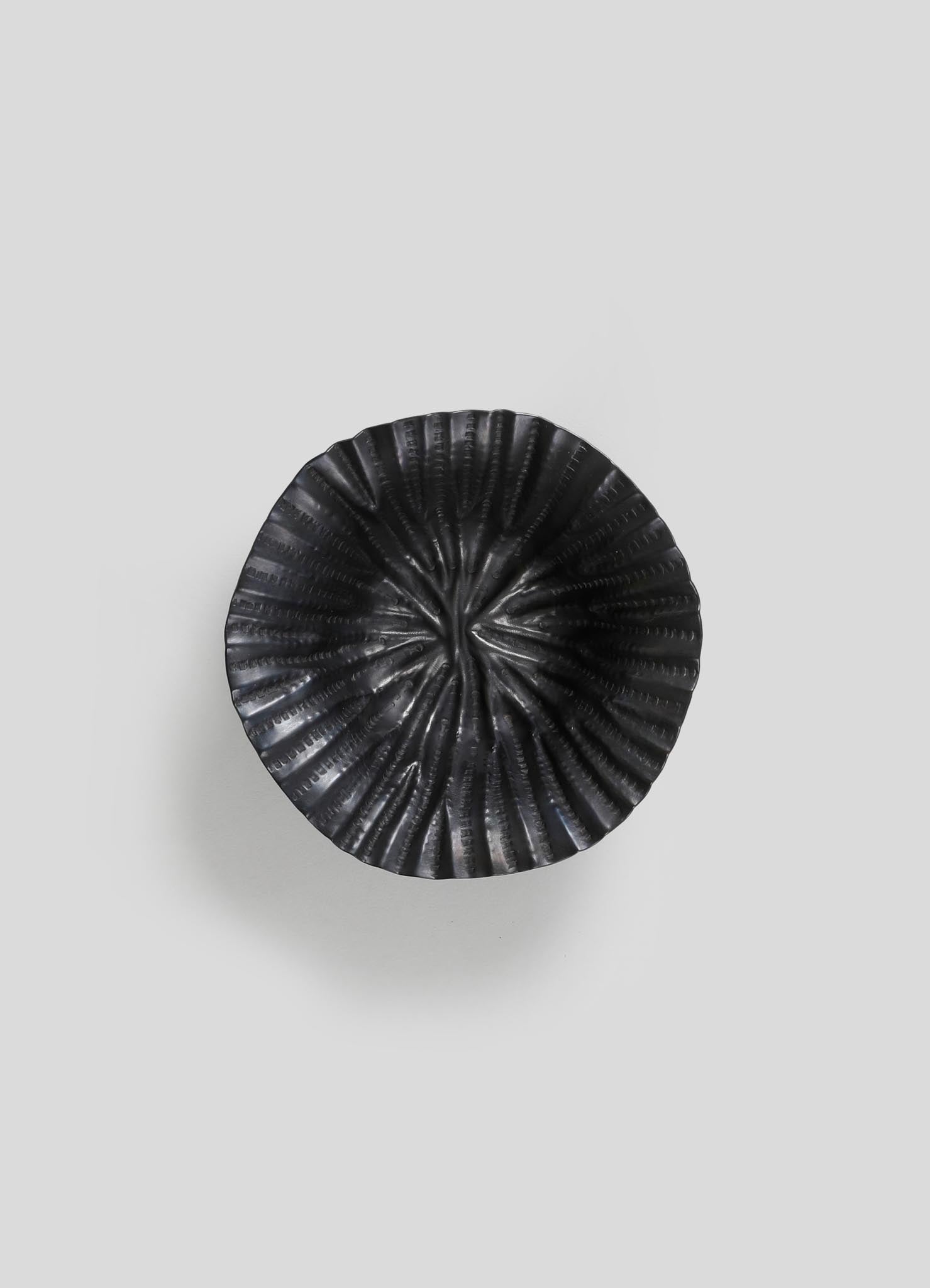 A black ceramic bowl with a ridged, spiral pattern and glossy finish, displayed against a plain light gray background.
