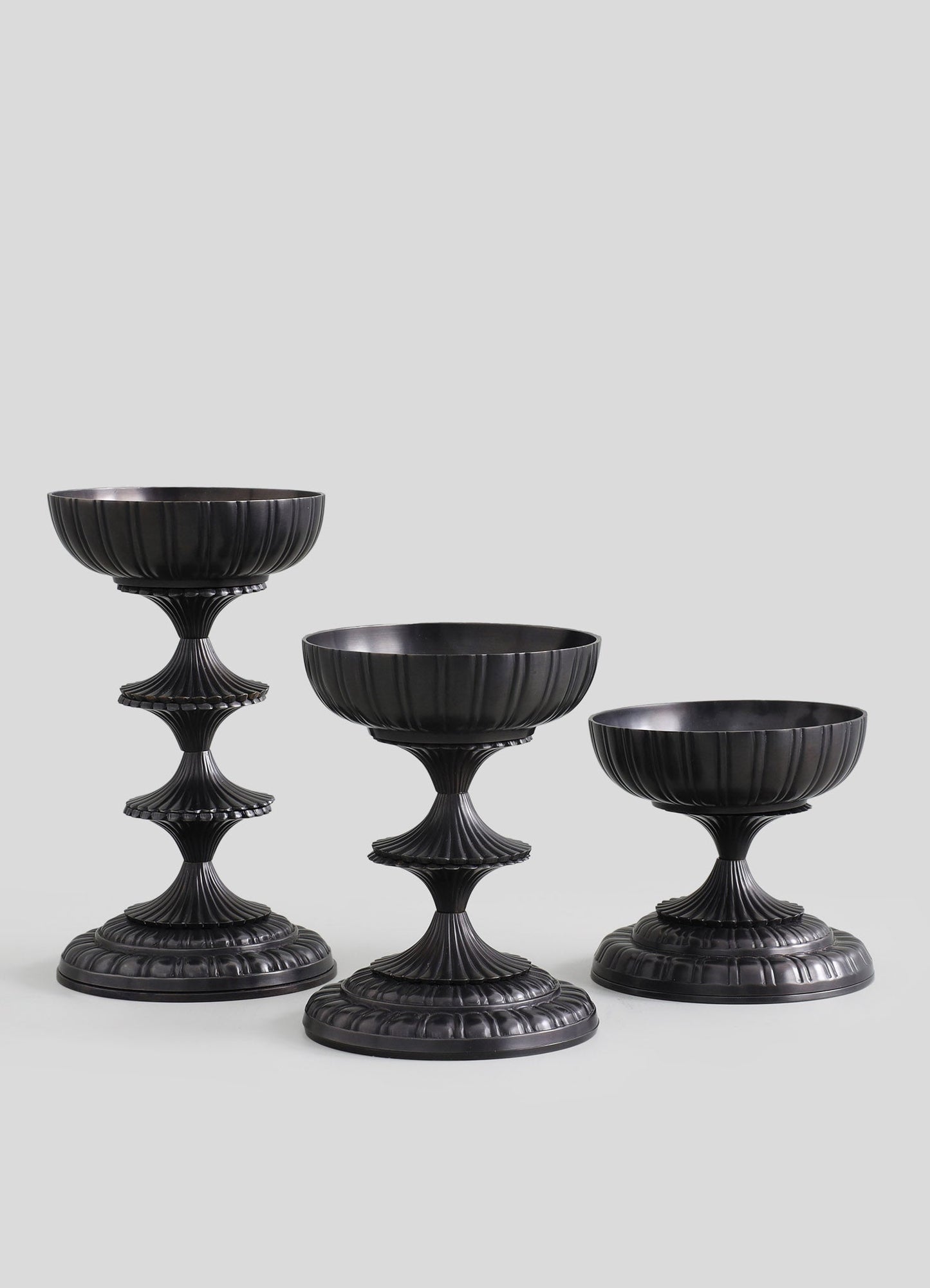 Set of three black bowls with ribbed texture and fluted bases, crafted from glossy material, featuring a vintage-inspired, ornate design with scalloped edges and tiered stems.