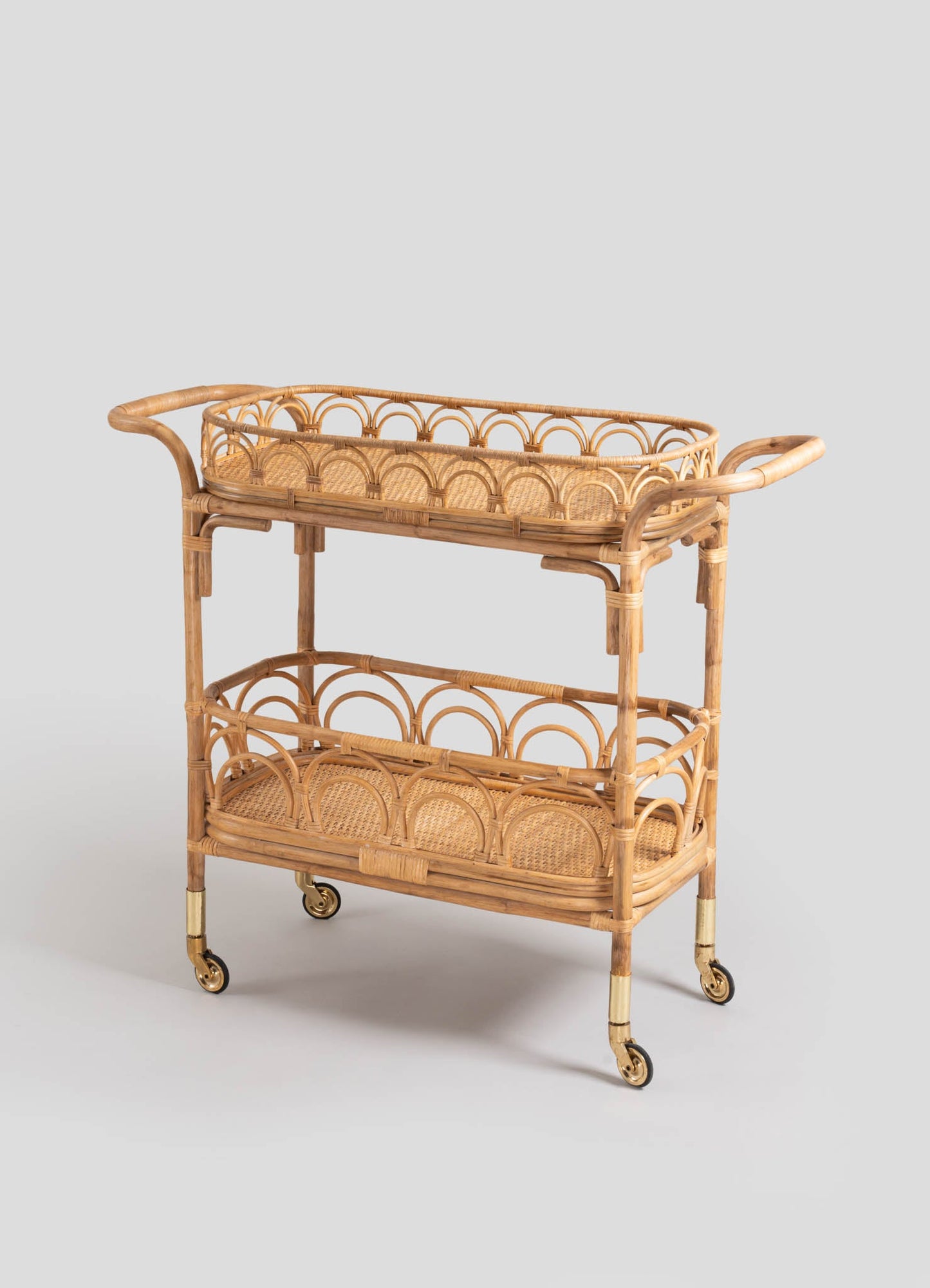 Wicker bar cart with metal casters featuring gold accents, constructed with curved bamboo frames and woven rattan shelves. The design showcases a light, natural wood tone with a handcrafted, airy appearance suitable for vintage or bohemian decor.