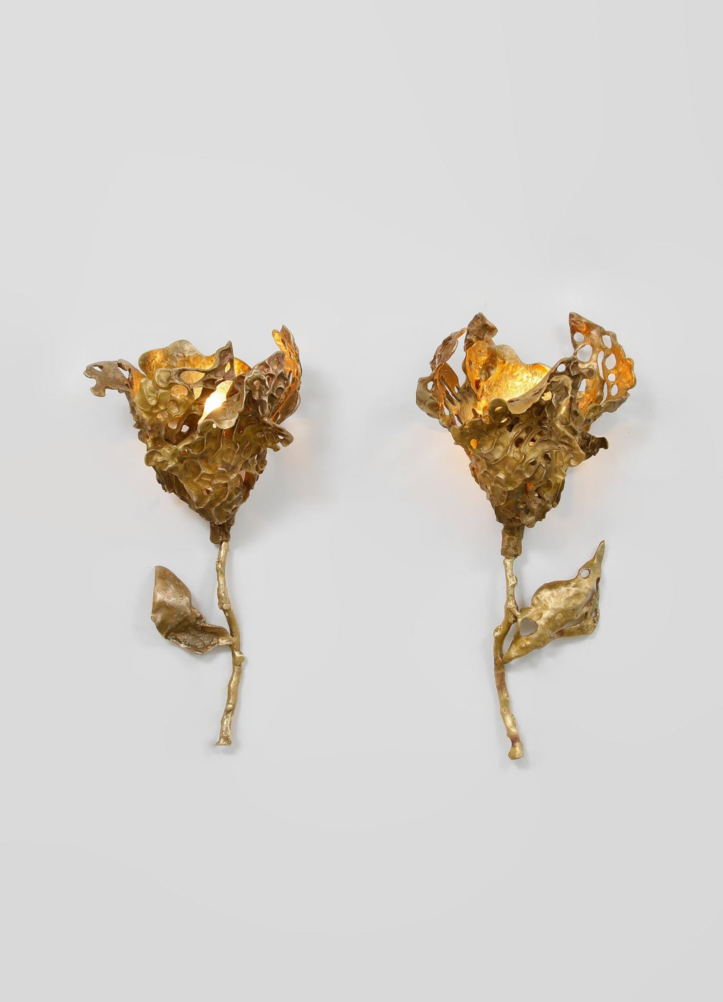 Pair of metallic gold earrings with textured, organic floral motifs and irregular, sculptural shapes, featuring intricate cutouts and a matte finish.