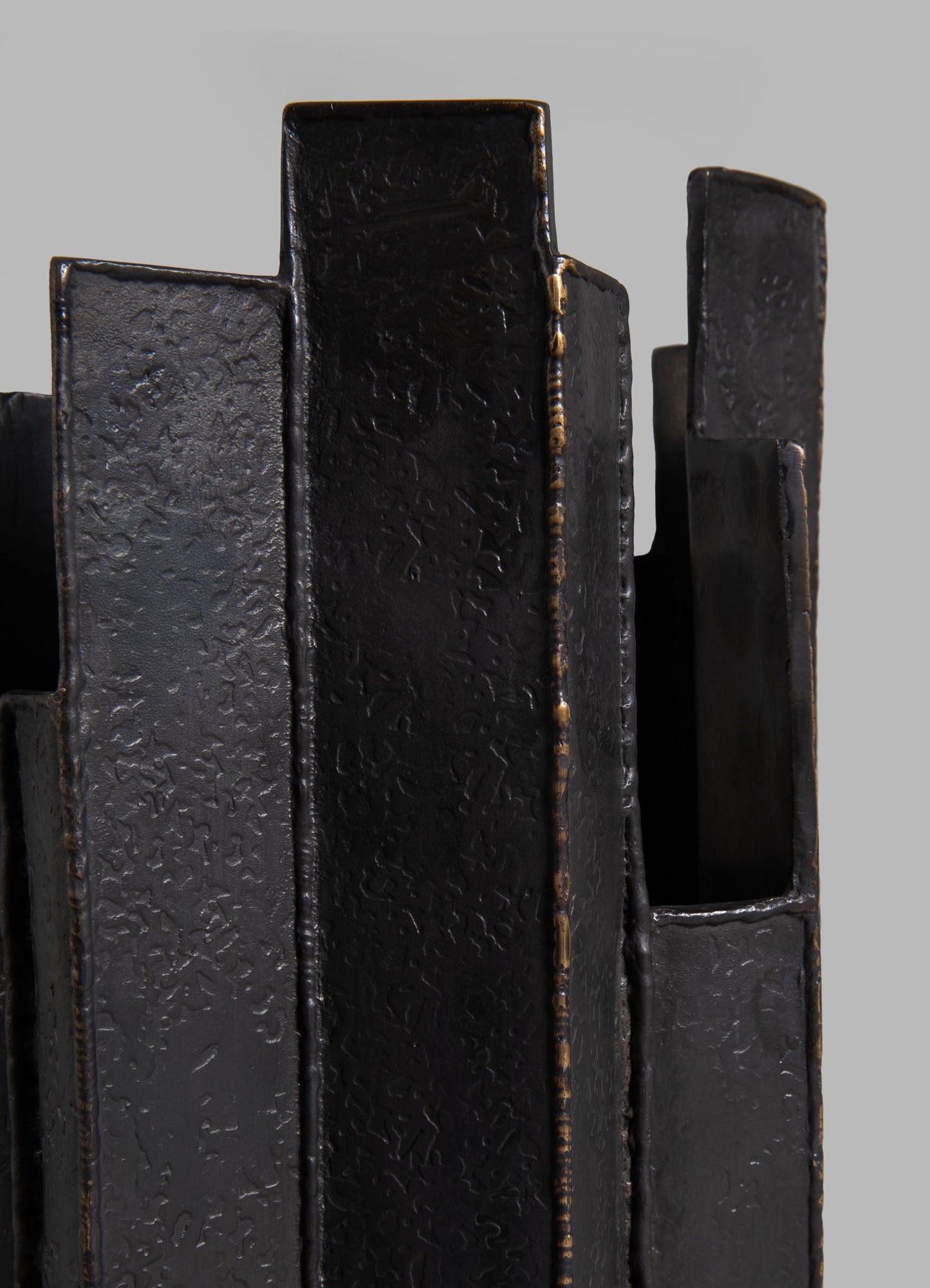 Black textured metal candle holders with irregular, organic surfaces and a matte finish, arranged in a grouping with varying heights.