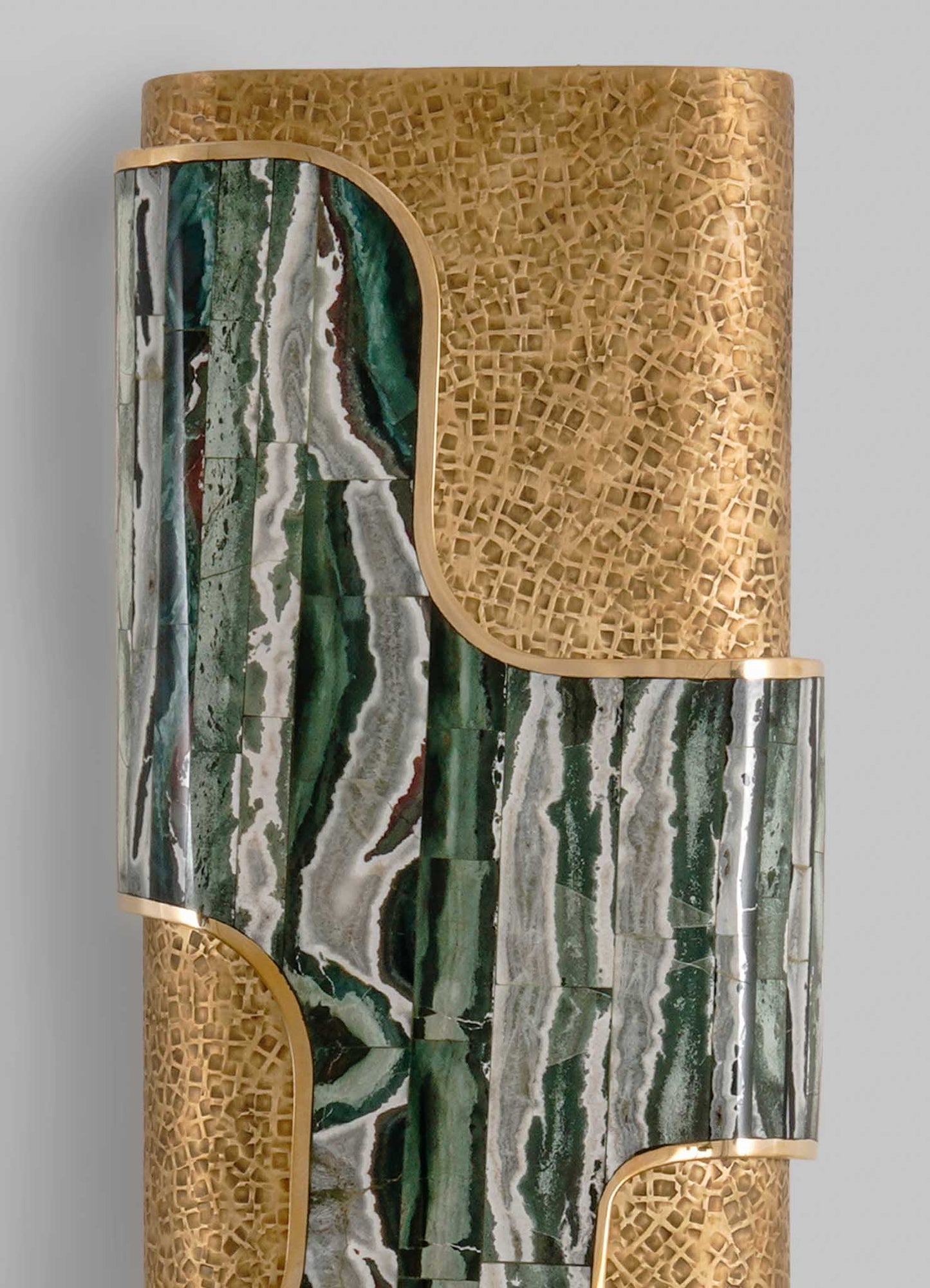 A decorative vessel composed of carved wood and polished marble or onyx in shades of green, white, and black, arranged in an abstract, curvilinear pattern with gold accents.