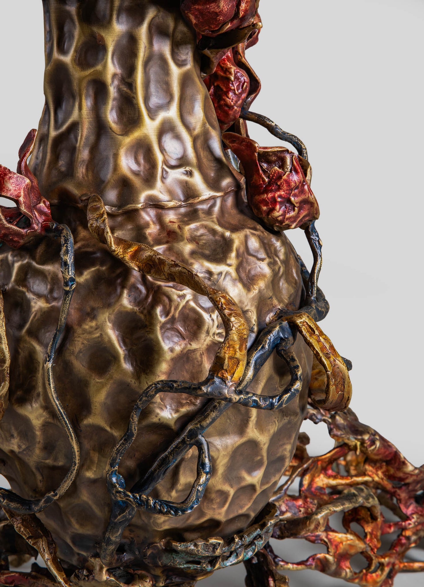 Sculptural ceramic vase with a textured, organic surface in earthy brown and beige tones, accented by twisted metallic branches in gold, bronze, and black, creating an abstract, nature-inspired design.