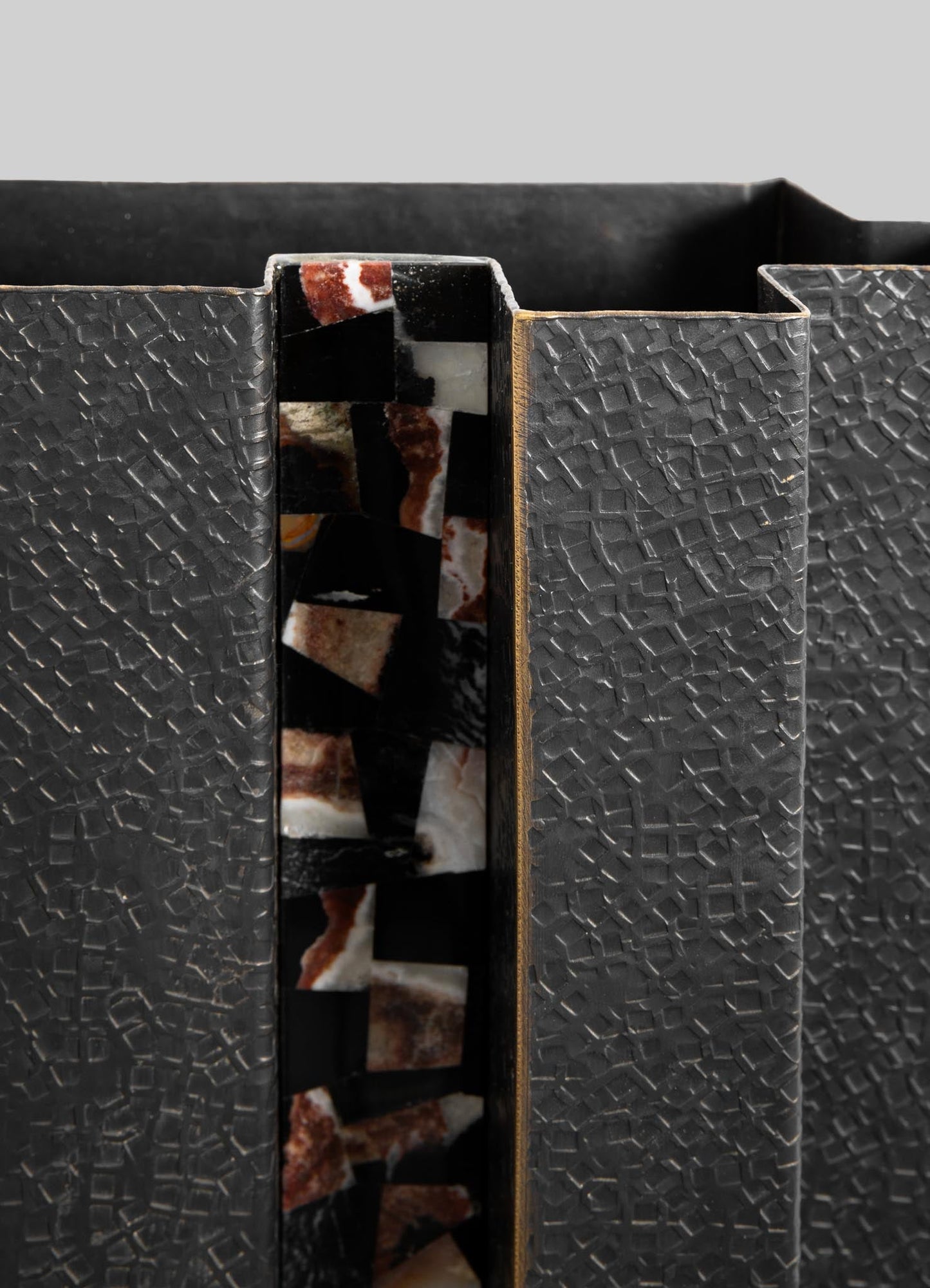 A black textured ceramic vase with a geometric pattern and a central stripe featuring abstract multicolored marble-like designs.