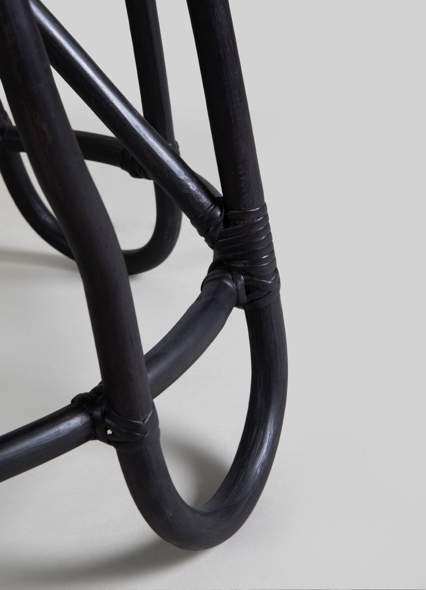 Black rattan furniture with a woven, curved design and a matte finish, featuring rounded shapes and a handcrafted style.