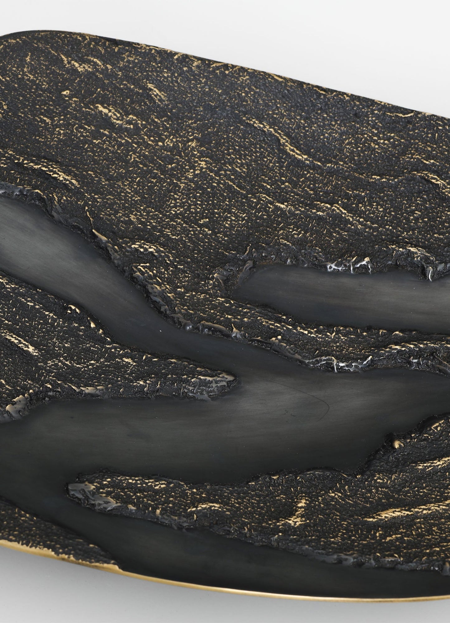 A close-up of a decorative tray with a black and gold textured surface, featuring intricate gold speckled patterns and smooth black accents, with a gold rim adding a touch of elegance.