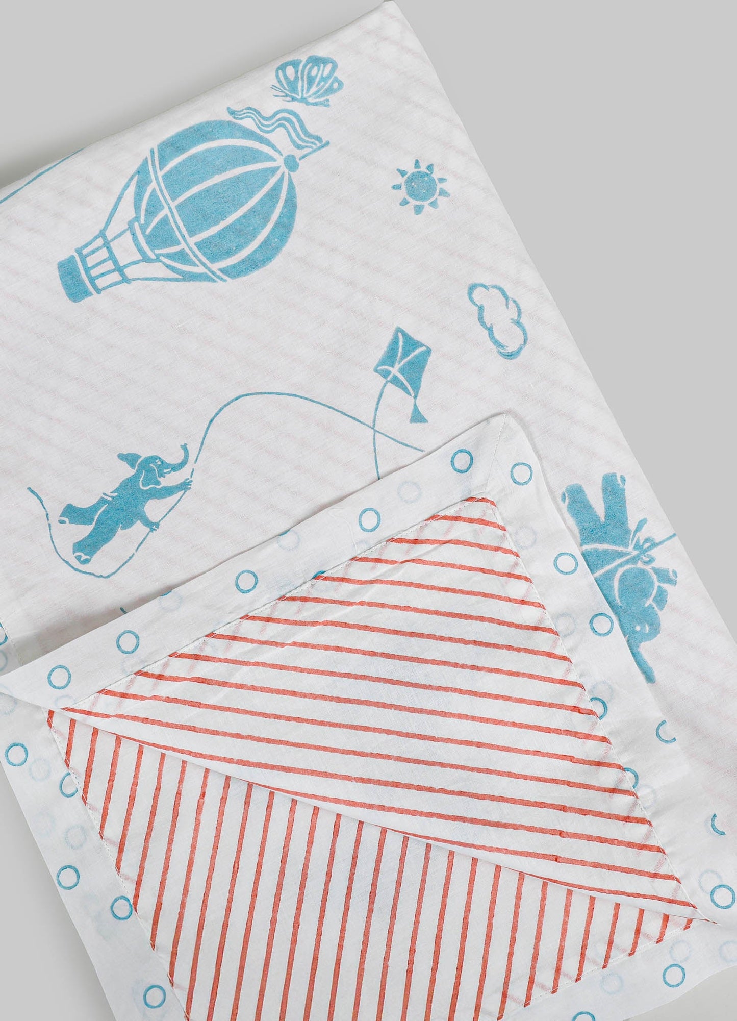 Children's cotton bedsheets featuring playful blue and red striped patterns with kite and balloon motifs, set against a white background. The design has a casual, cheerful style suitable for a kid's room.