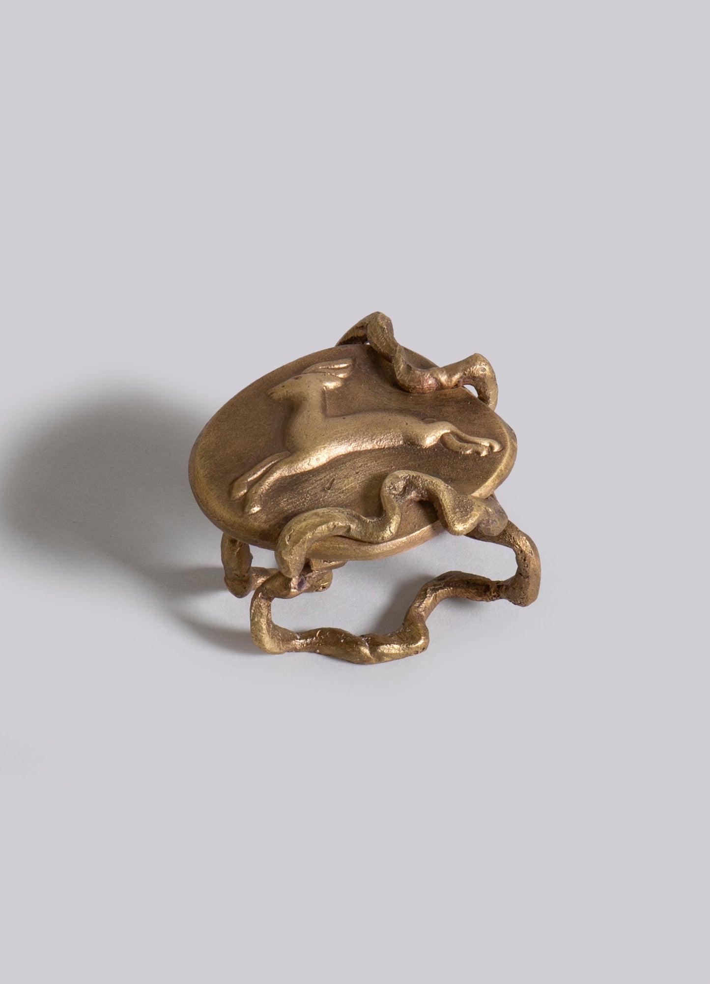 A brass ring featuring a raised horse motif and an irregular, organic shape with textured edges.