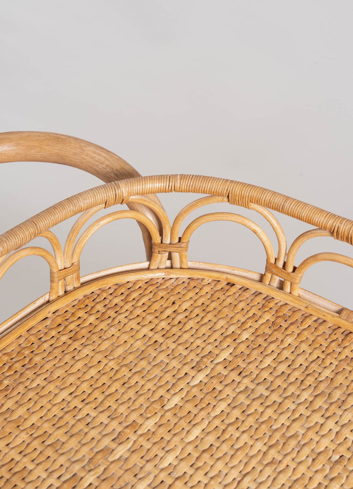 Wicker chair with a rounded woven seat and a curved rattan backrest, featuring a natural wood finish and intricate weaving patterns.