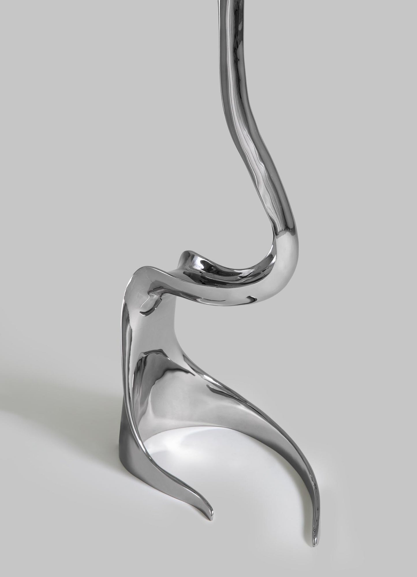 Silver earring with a curved design on a light gray background viya designer luxury table lamp