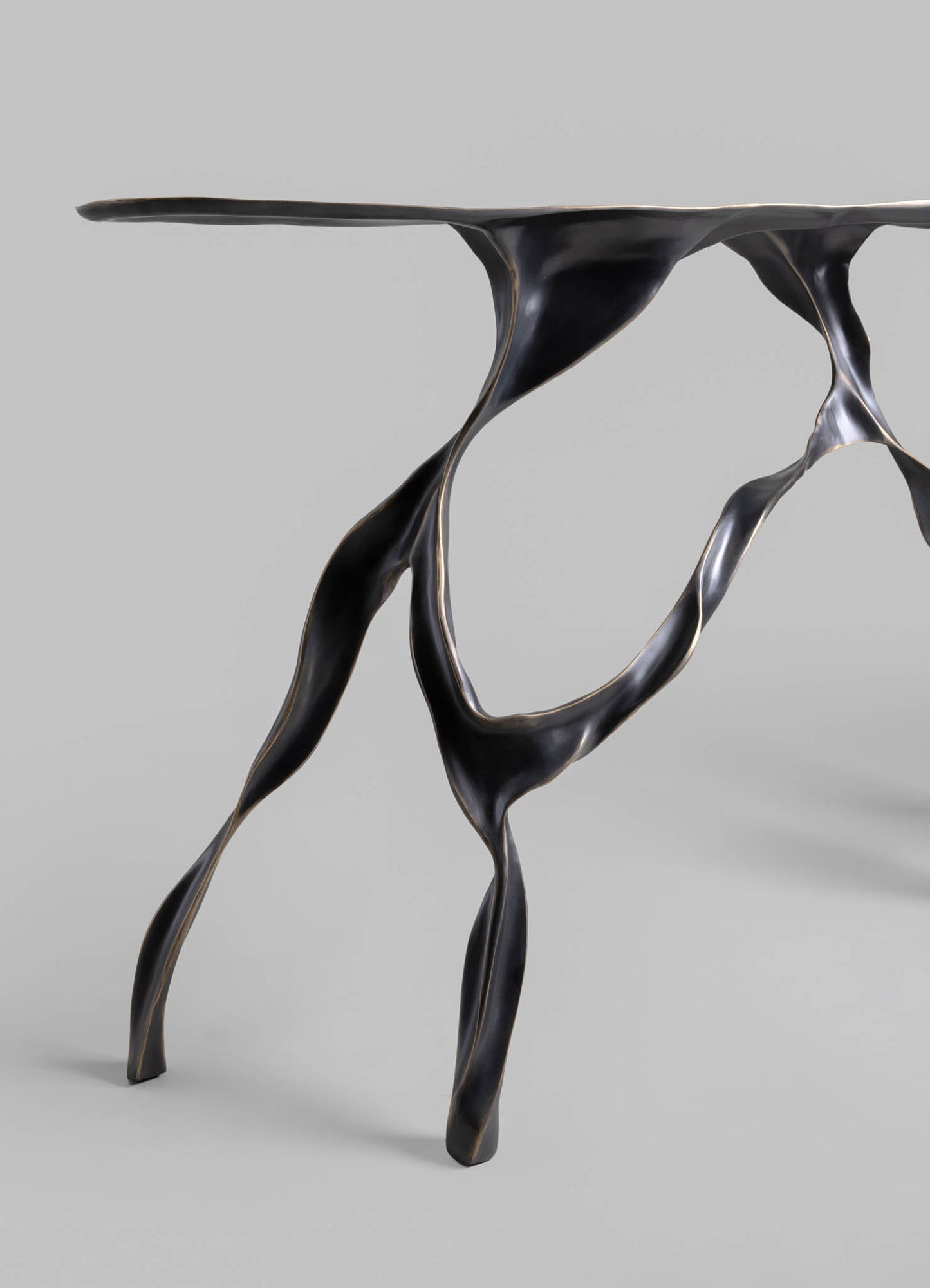A black metal console table with organic, sculptural lines and a wavy surface, featuring a glossy finish and a contemporary style.