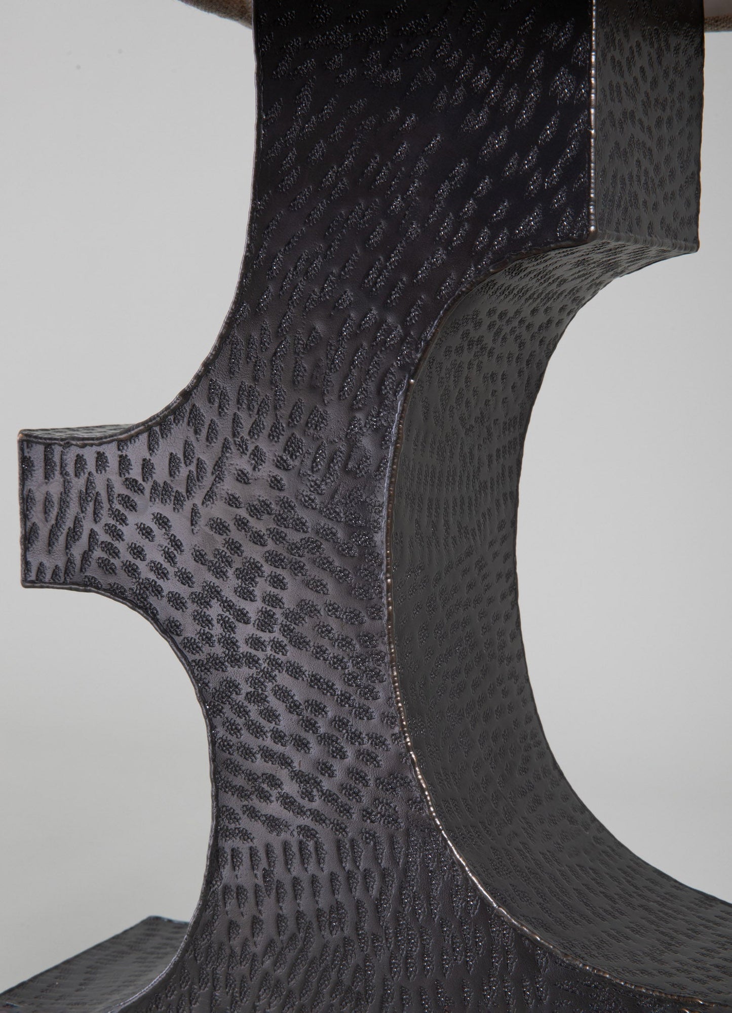 Close-up of a black leather surface with a textured, embossed pattern resembling animal skin, featuring curved lines and a glossy finish. The material appears to be high-quality leather or faux leather, emphasizing a contemporary and sophisticated style.