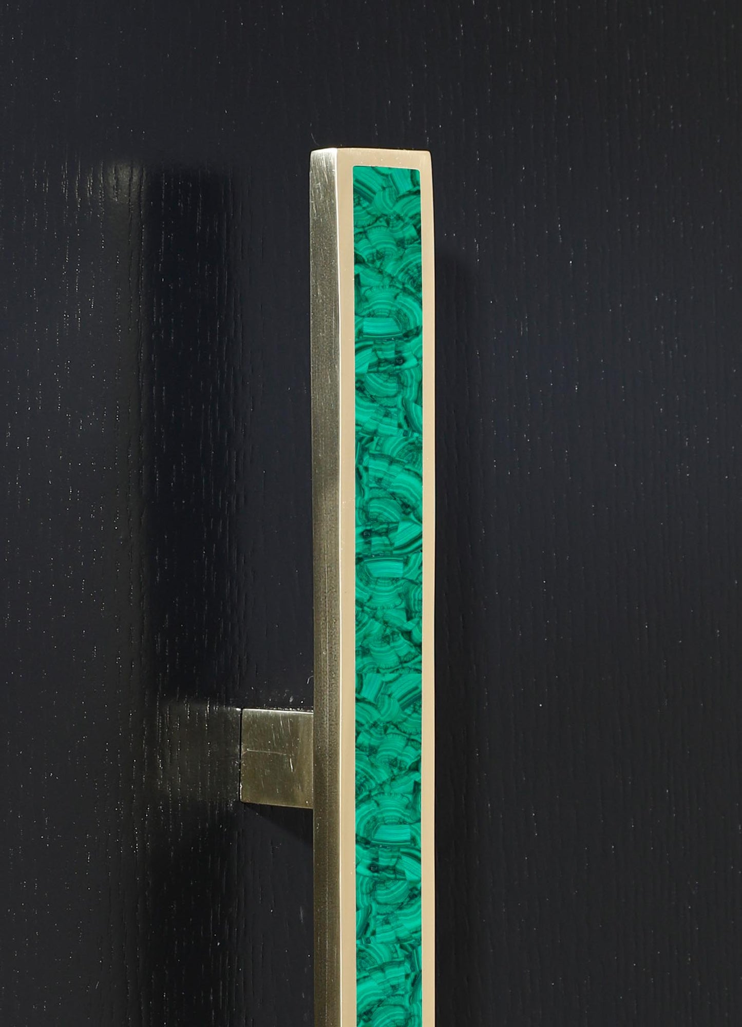 A close-up of a metal doorknob with a rectangular turquoise inlay featuring swirling, marbled patterns, set against a black textured door.