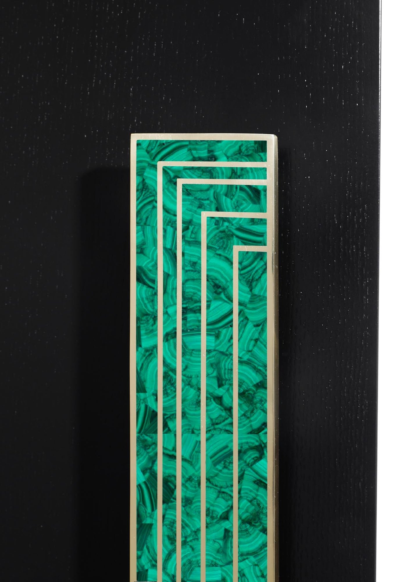 A decorative panel with a geometric design featuring thin metal lines on a green and black malachite-patterned background, mounted on a black wall.