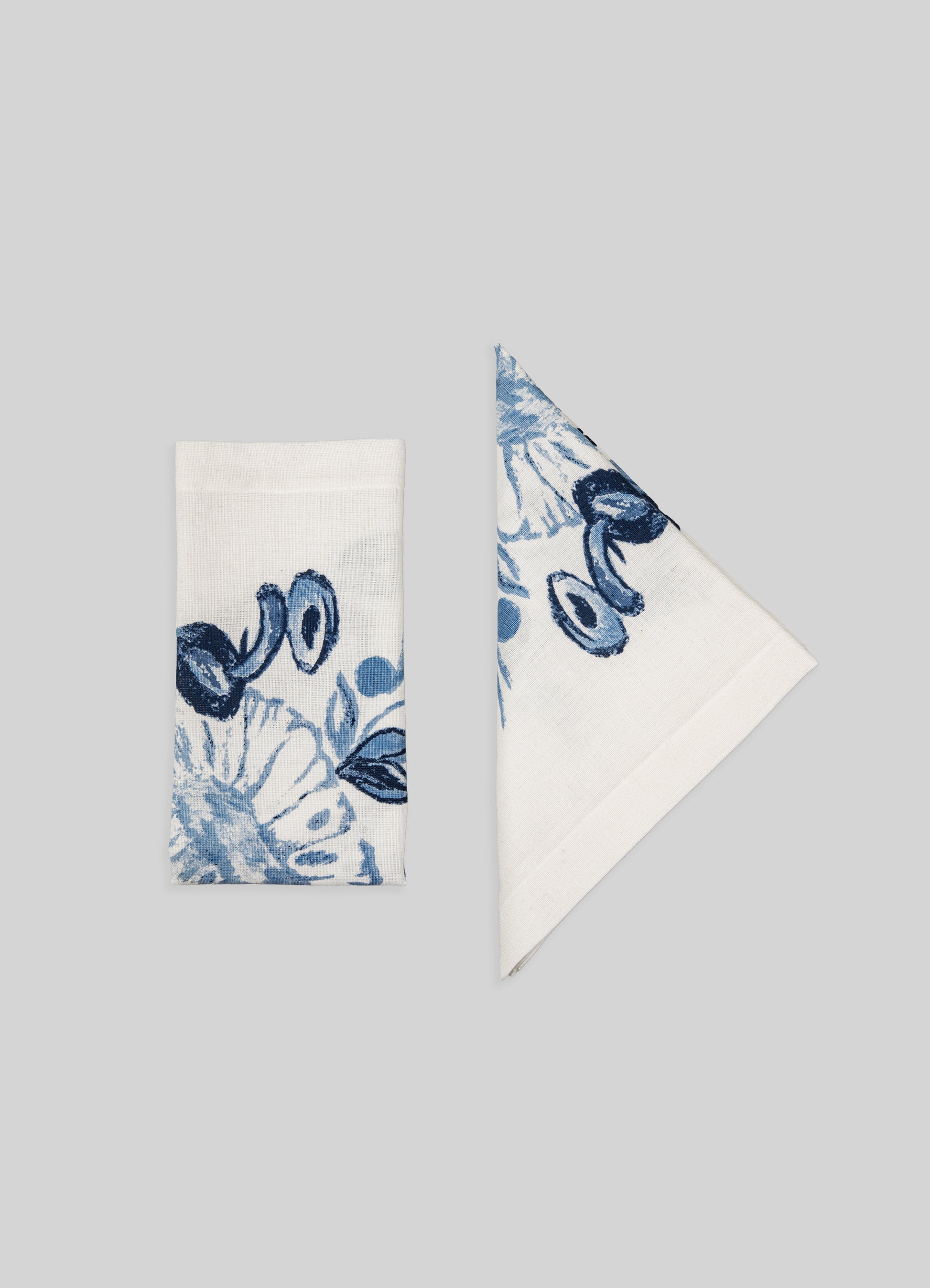 Cotton napkins with blue floral and abstract motifs, featuring a white background and finished edges. The design combines traditional and contemporary styles, emphasizing handmade textile craftsmanship.