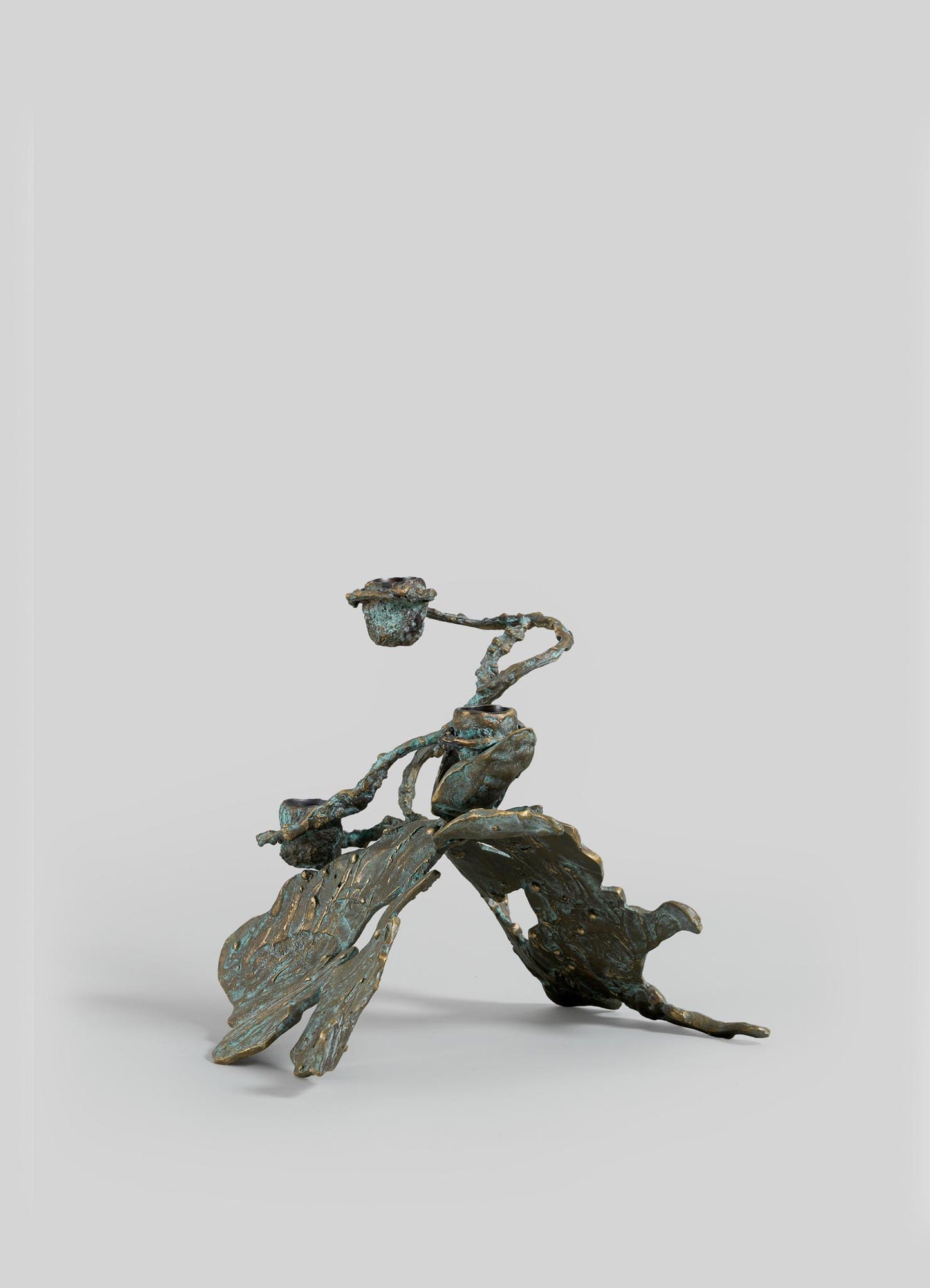 The VIYA Butterfly Candle Stand Small features a bronze, textured organic form with abstract oak leaves and acorns, displayed against a plain light gray background.