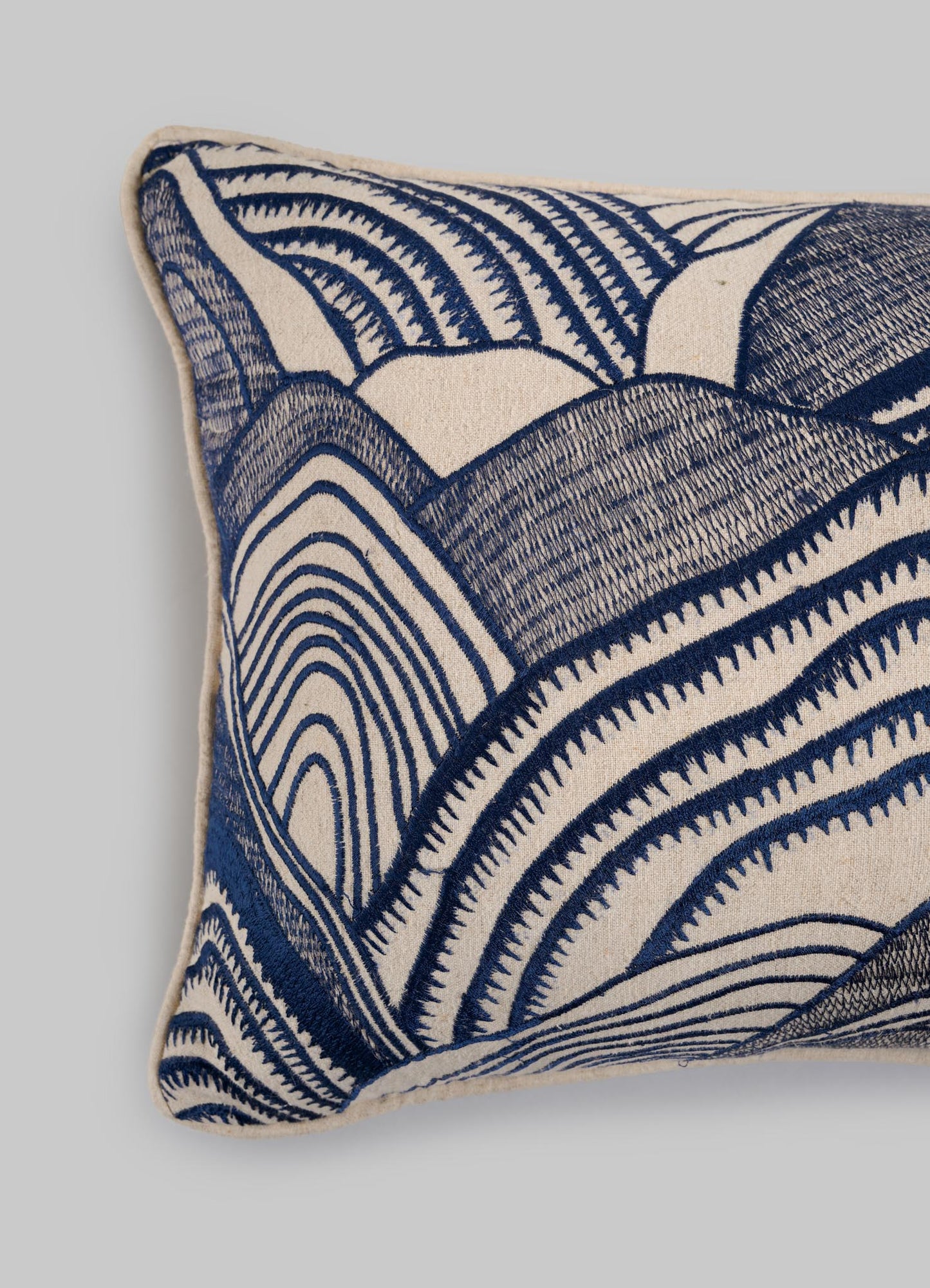 The Viya Dreamscape Blue Embroidered Mounds Cushion Cover 12"x18" is a rectangular beige cover with abstract blue embroidery, inspired by symbolic textile motifs, shown against a plain gray background.