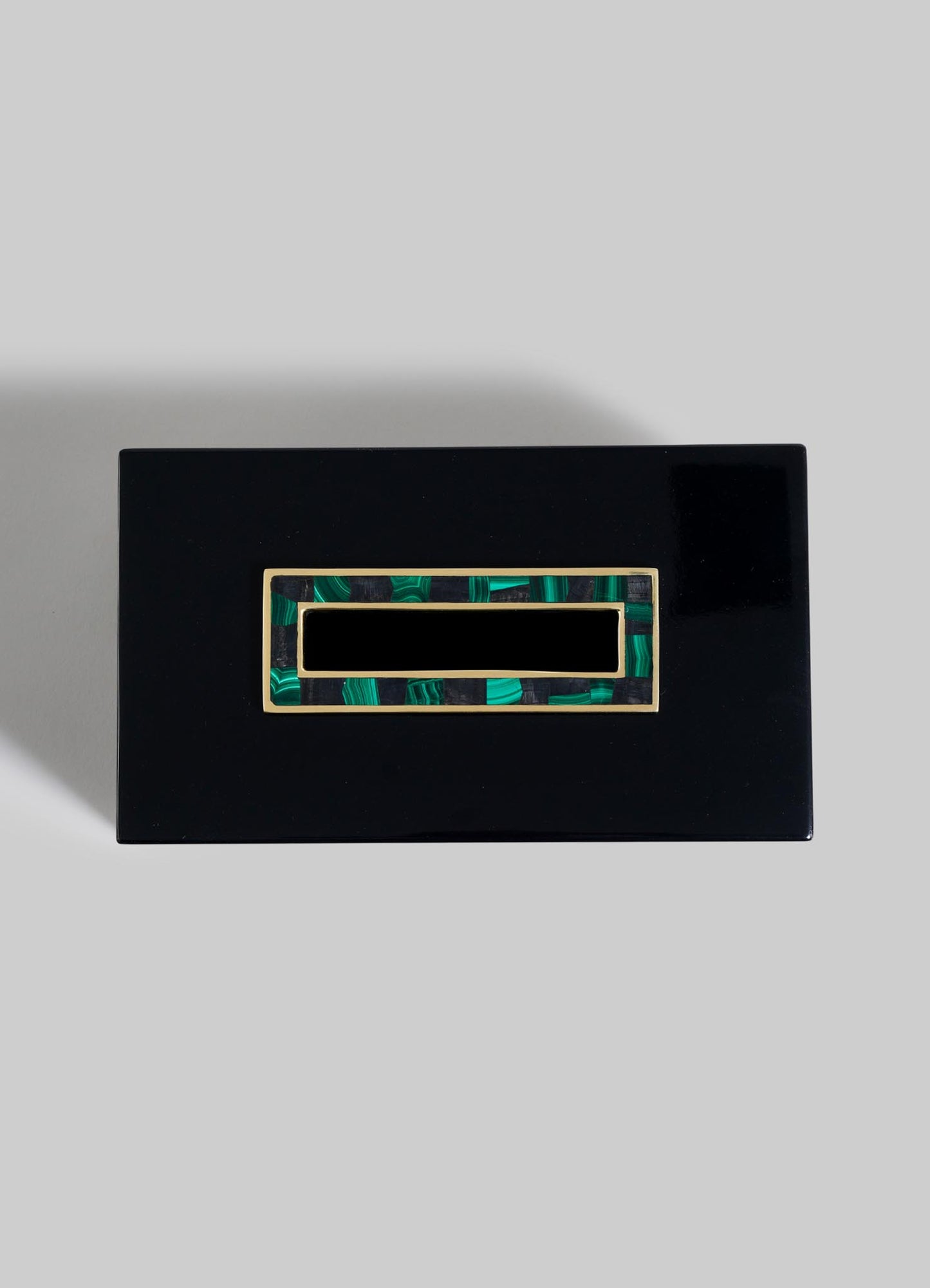 The VIYA Rivoli Tissue Box is a rectangular black lacquered piece with a glossy finish and an Art Deco-inspired green and gold inlay on the lid, evoking Bombay cinema halls, shown on a plain light gray background.