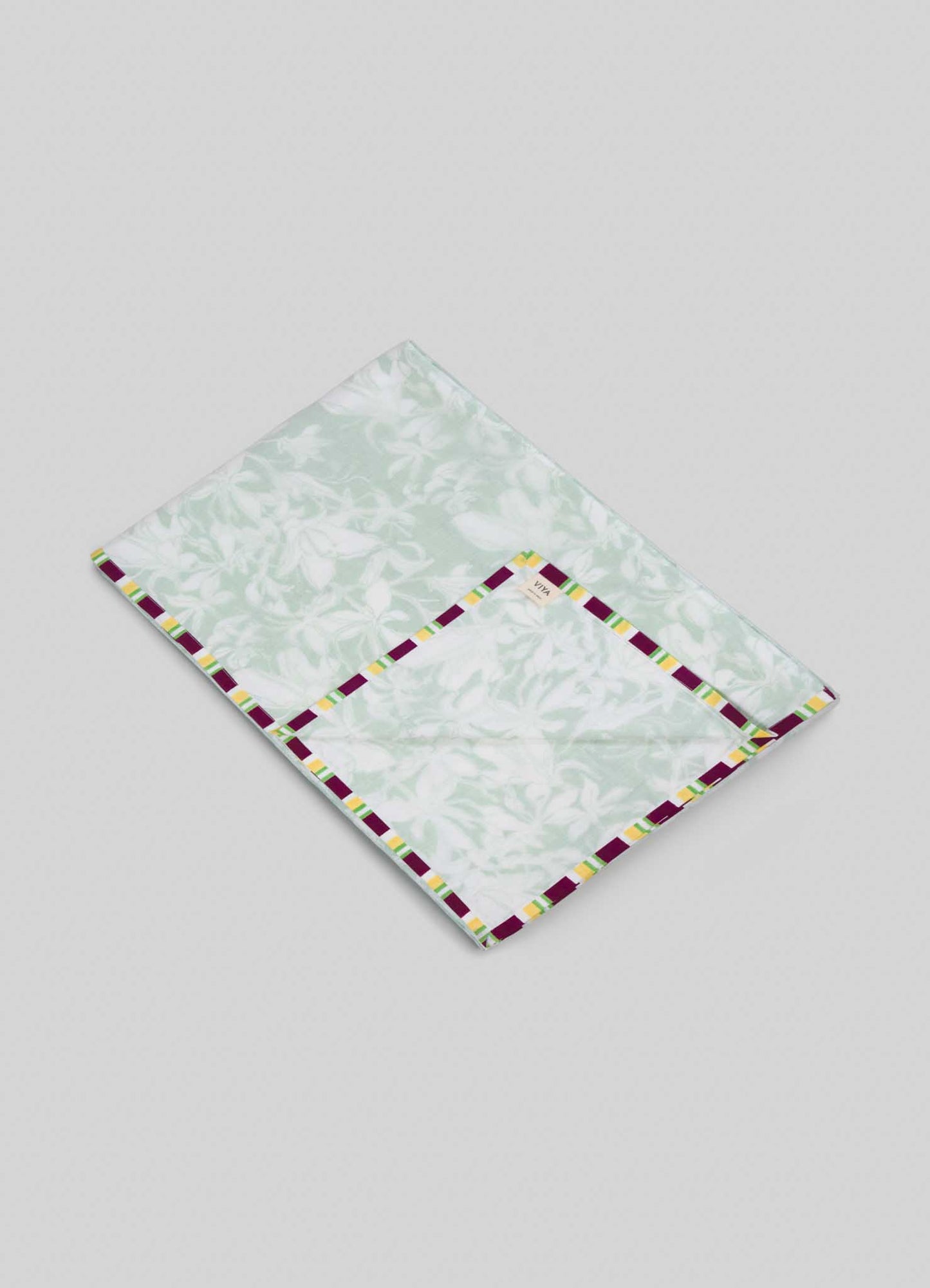 The Viya Spring Bouquet Green King Size Dohar features a light green and white floral pattern inspired by Indian garden bedding, with a yellow, white, and dark red geometric border, shown on a plain light gray background.