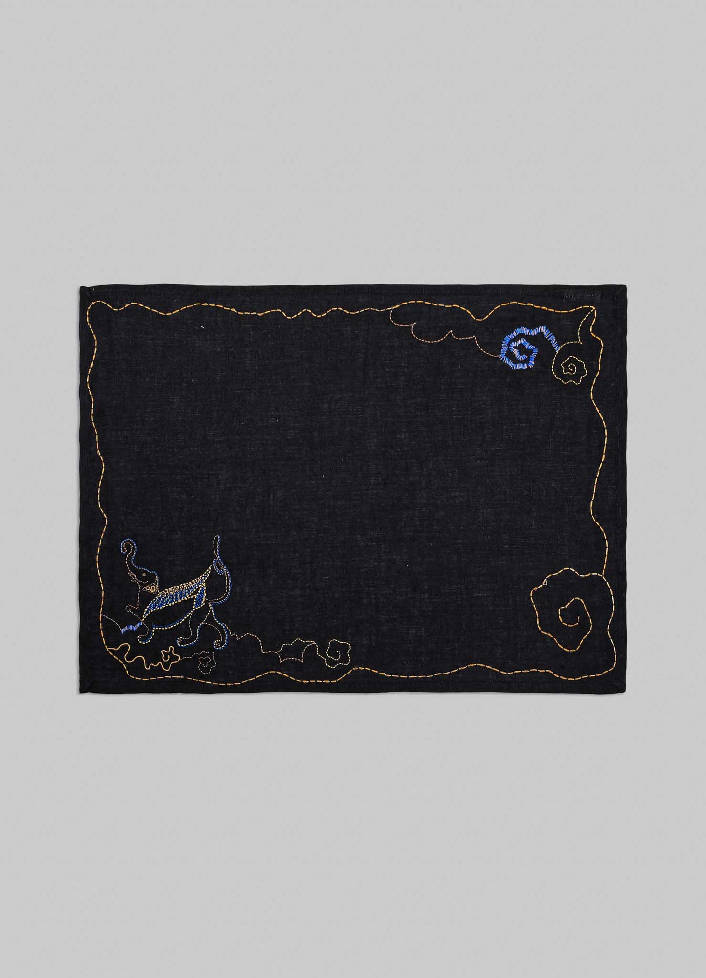 Embroidered black fabric patch with decorative elements on a gray background viya luxury placemats