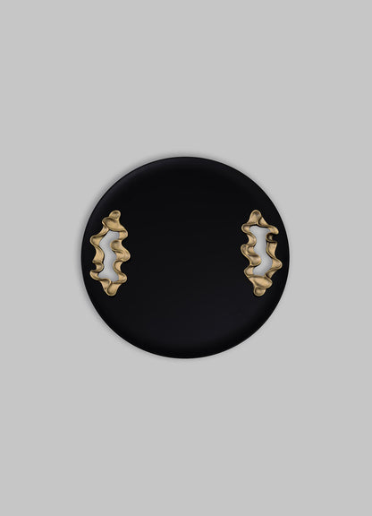 A black round tray with gold, abstract-shaped handles, made of metal, has a contemporary style with a smooth matte finish.