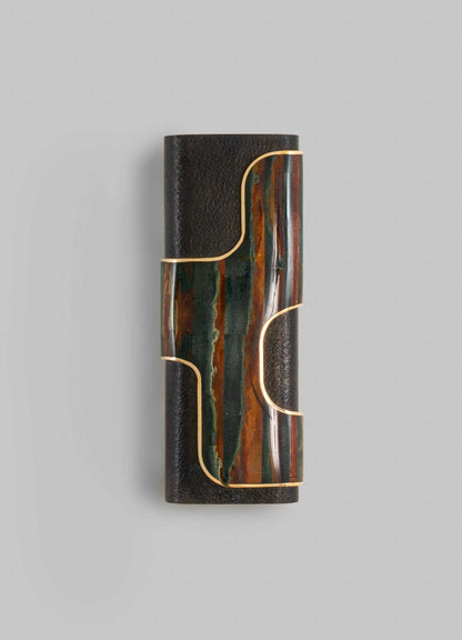A decorative wall sconce featuring a cylindrical black textured finish with a central panel of multicolored onyx or marble slices and gold-toned metal accents, creating a modern luxury style.