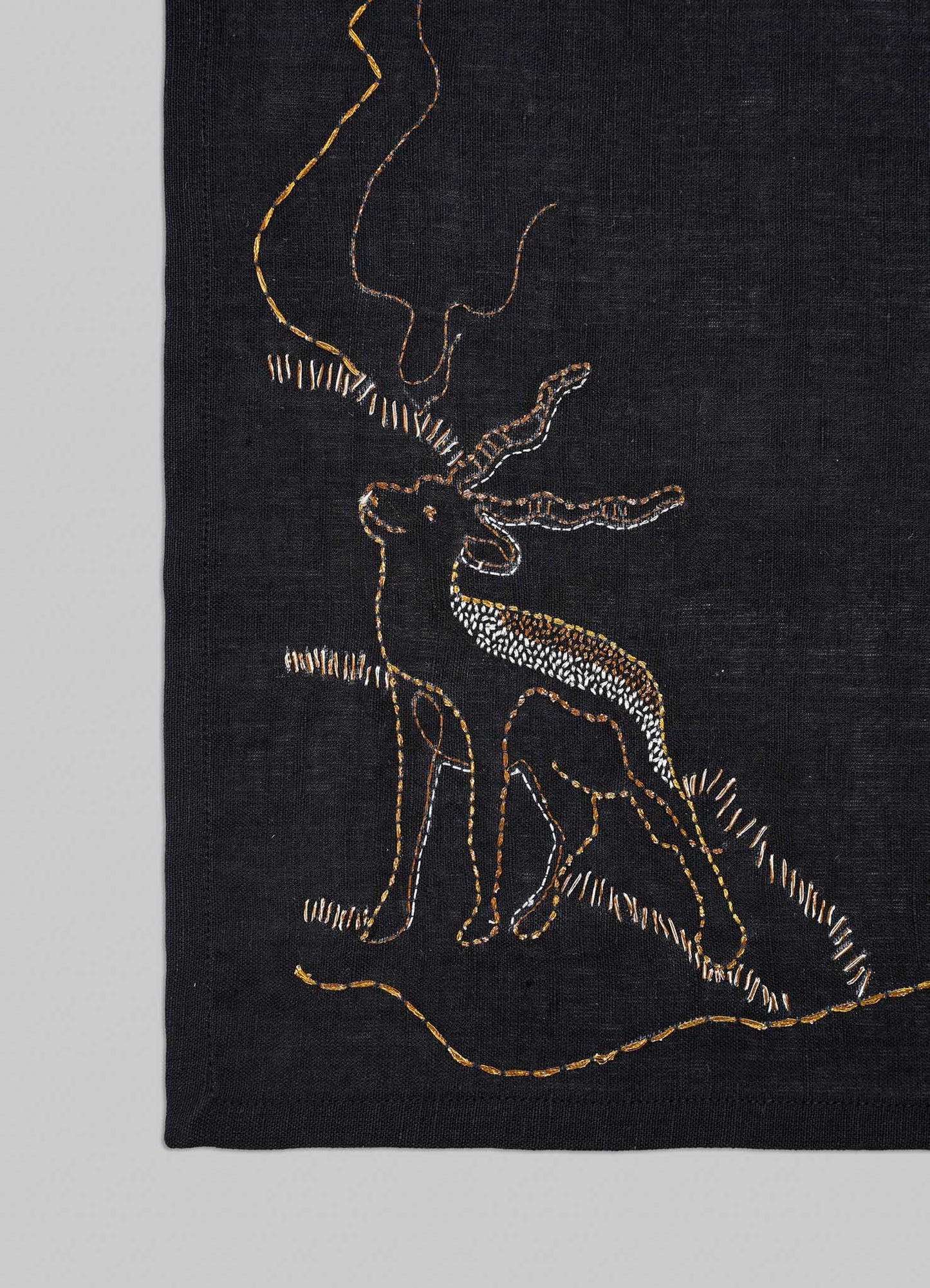 Black fabric with gold embroidery of a deer on a gray background viya luxury placemats