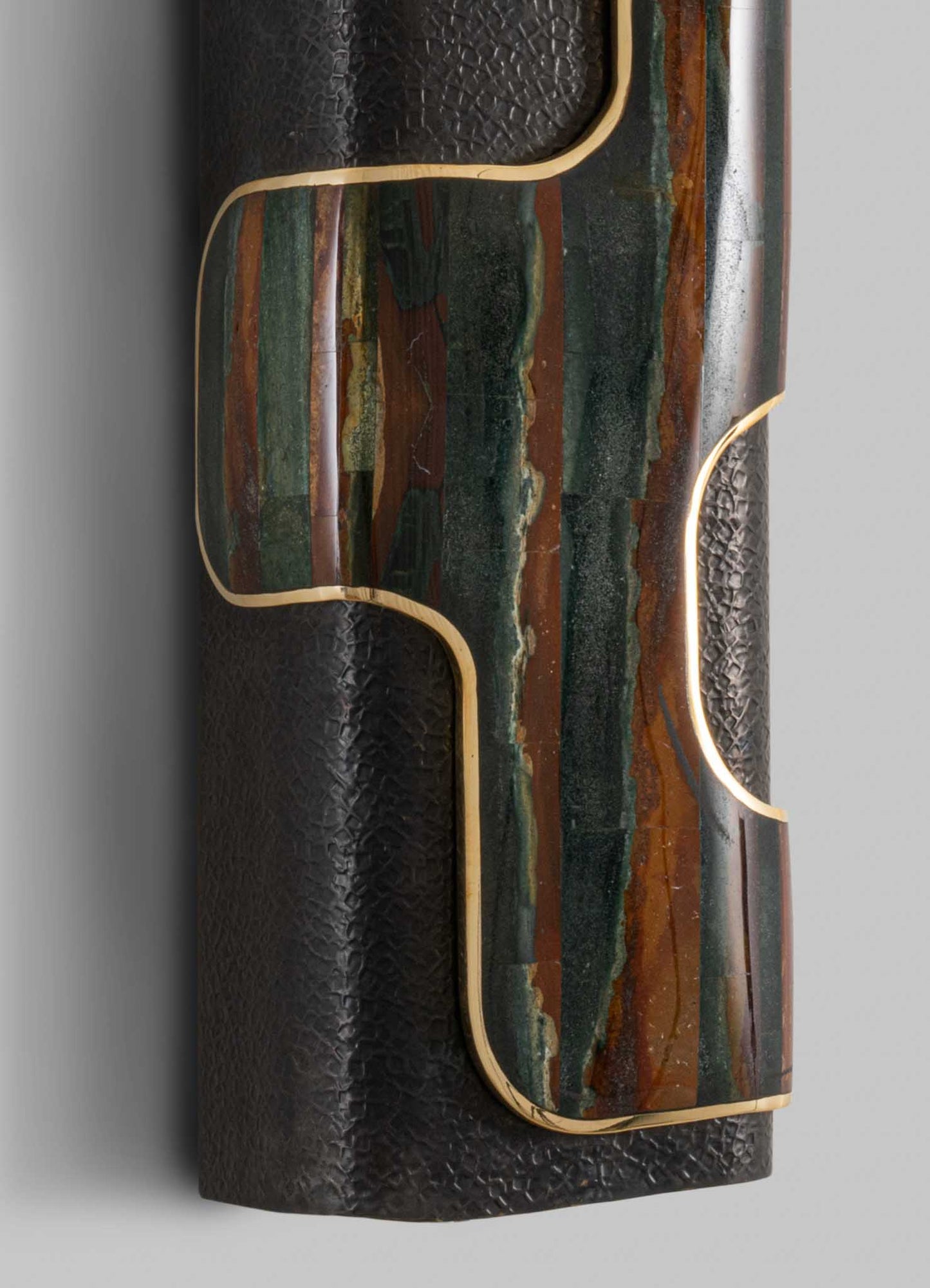 A rectangular coffee table with a geometric design, featuring a polished stone top with shades of green, brown, and black, accented by gold-colored metal edges, set on a textured black base.