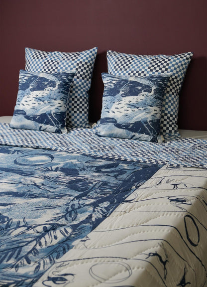 Bed with blue and white patterned bedding and pillows covers against a dark purple wall luxury cotton quilts viya