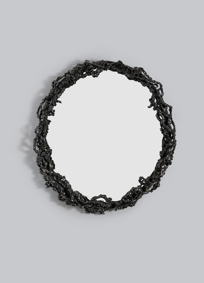 The VIYA Andaman Mirror features a round design with an intricate, irregular black metal frame inspired by organic vines and branches, mounted against a plain light gray background.