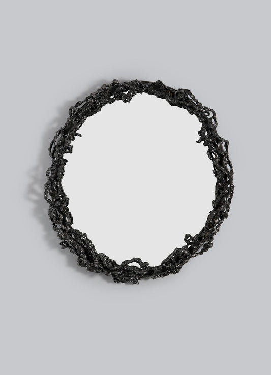 The VIYA Andaman Mirror features a round design with an intricate, irregular black metal frame inspired by organic vines and branches, mounted against a plain light gray background.