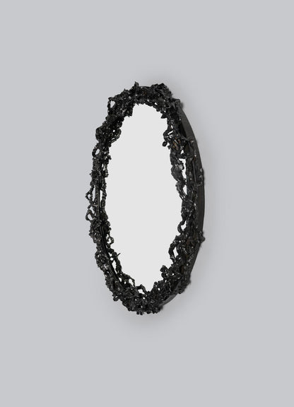 The VIYA Andaman Mirror features an oval shape with a textured black frame inspired by organic forms of Andaman caves, displayed against a plain gray background.