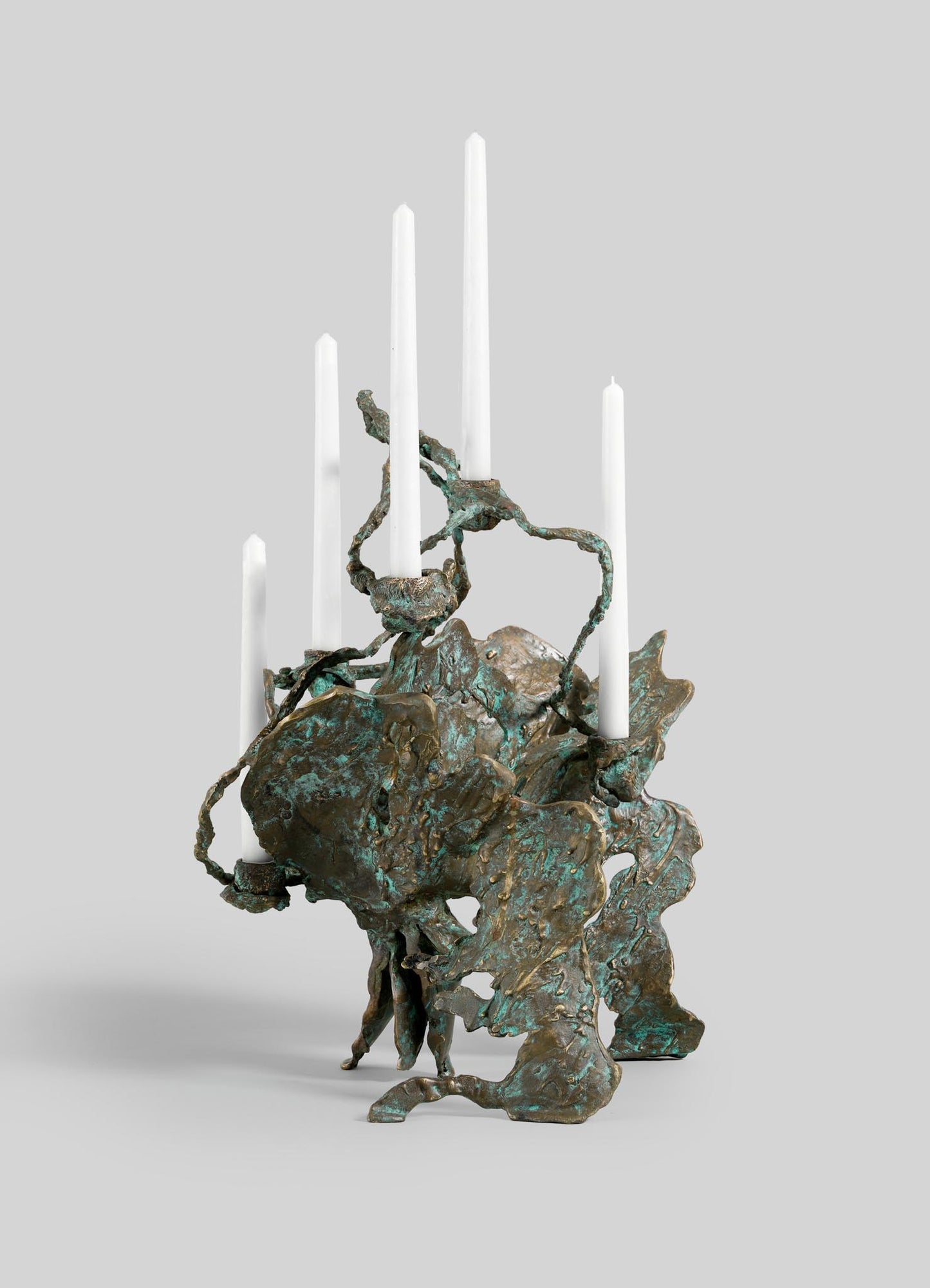 The VIYA Butterfly Candle Stand Large is a sculptural bronze candelabra with an organic, abstract form and a textured, oxidized greenish patina. It holds six white taper candles at varying heights.