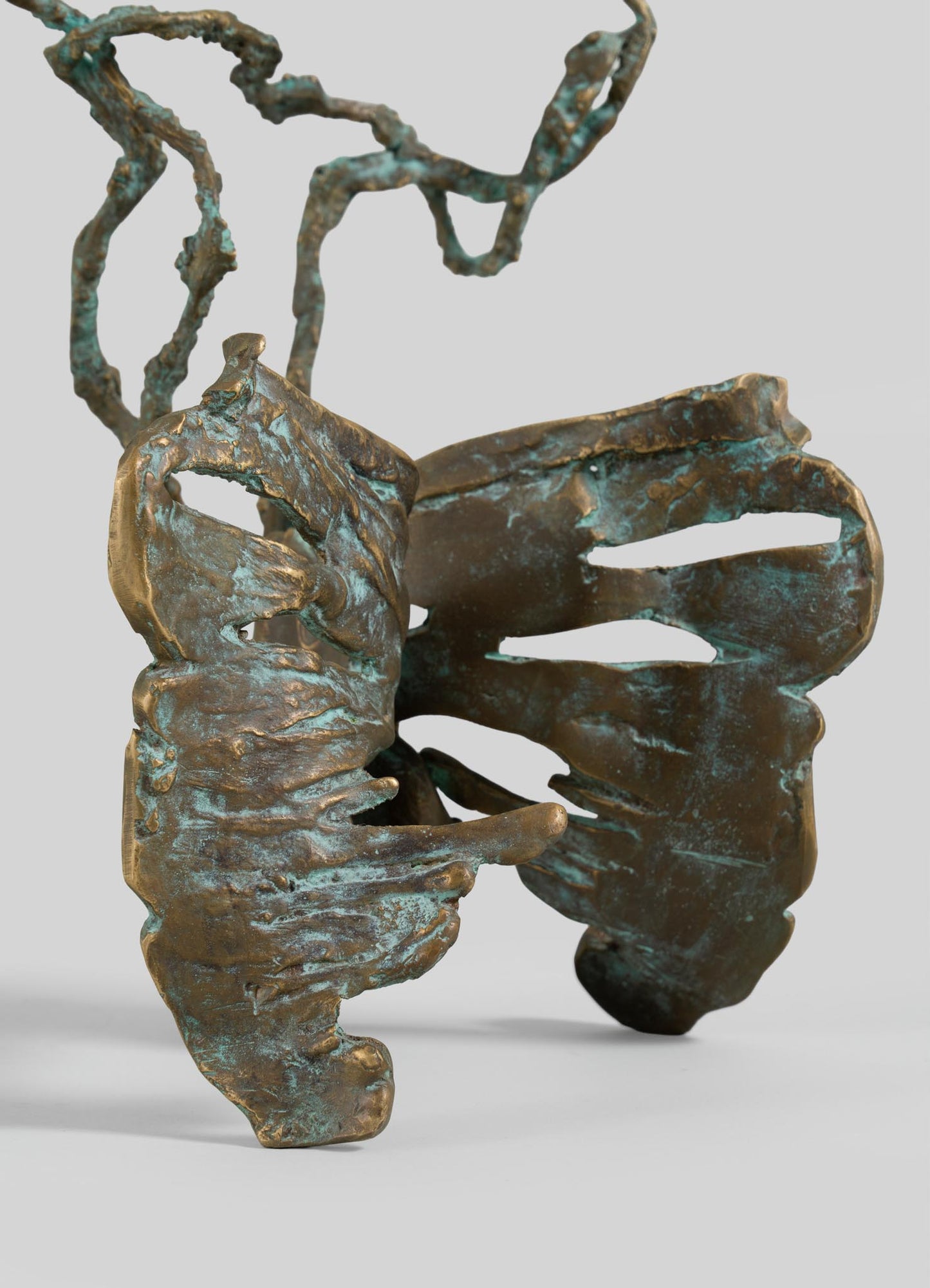 The VIYA Butterfly Candle Stand Medium is a bronze sculpture featuring abstract, wing-like shapes and twisting, branch-like forms with a textured patina finish.