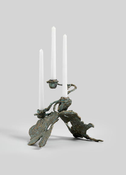 The VIYA Butterfly Candle Stand Small is a sculptural bronze candelabrum with three white candles and abstract, textured leaf-shaped arms and base, displayed against a plain light gray background.