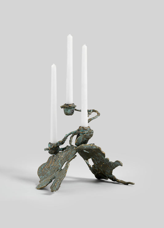 The VIYA Butterfly Candle Stand Small is a sculptural bronze candelabrum with three white candles and abstract, textured leaf-shaped arms and base, displayed against a plain light gray background.