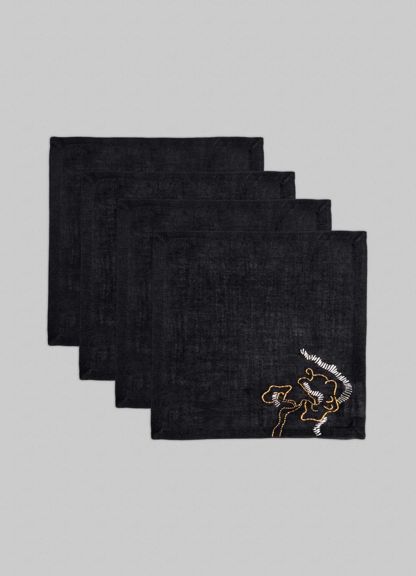 Set of four Viya Blackbuck Dreams Hand Embroidered Black & Gold Cocktail Napkins, each featuring a gold rooster motif on black fabric, neatly stacked against a light gray background.