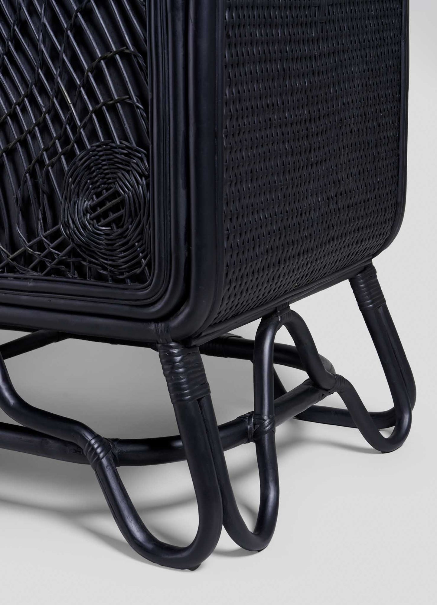 Close-up of the corner and legs of the VIYA Chakra Cabinet, showcasing intricate cane weaving, a curved frame, and tubular legs connected at the base for a stylish chakra decor touch.