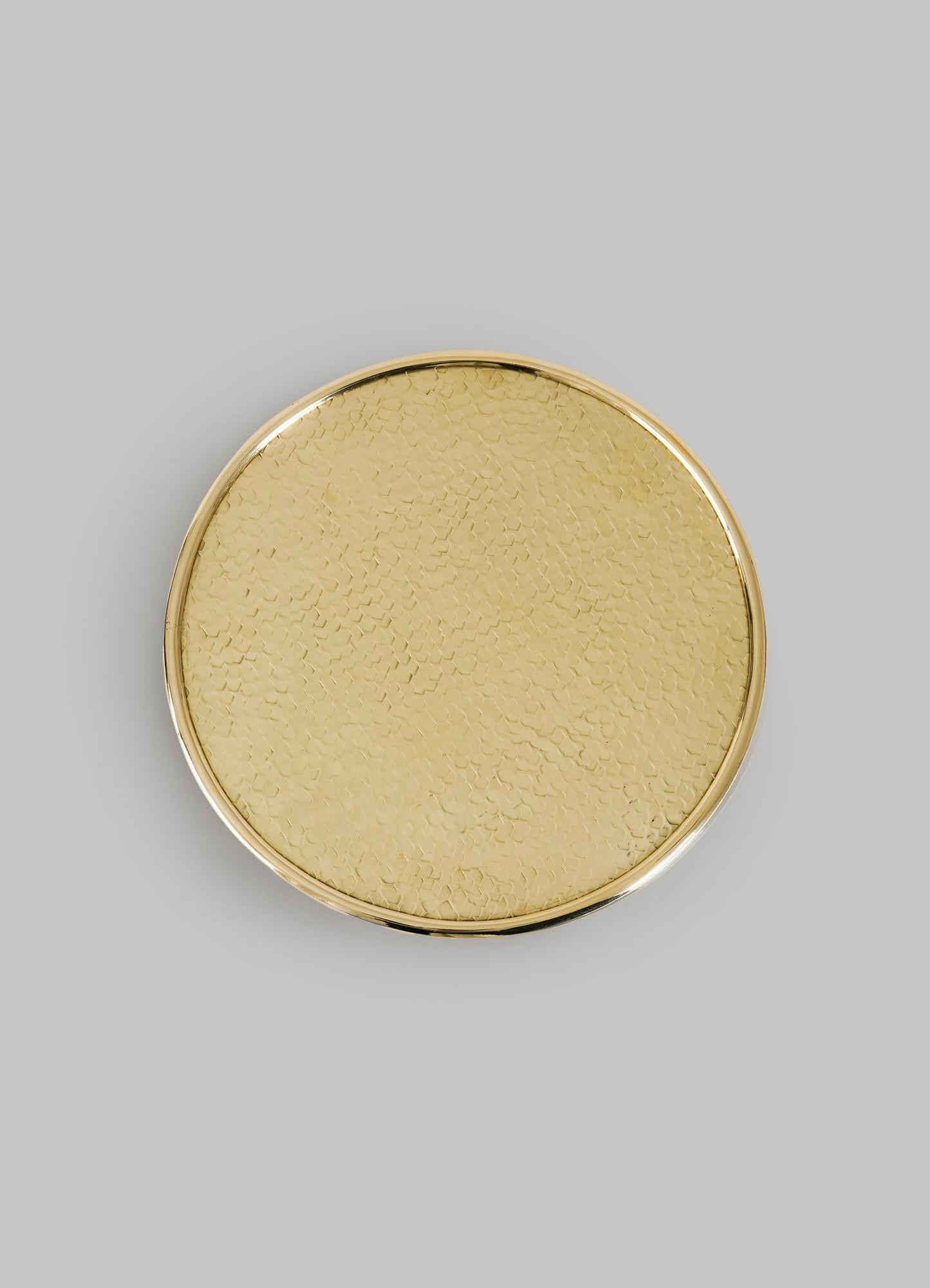 The VIYA City Palace Cake Platter is a round, gold-toned handcrafted brass tray with a hammered texture and smooth raised edge, inspired by Jaipur in Bloom, shown on a plain light gray background.
