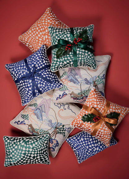 The Dreamscape Orange Embroidered Checks Cushion Cover 12"x18" by Viya is arranged with other festive pillows on a red background. It features a nature-inspired orange check motif, perfect for holiday décor.