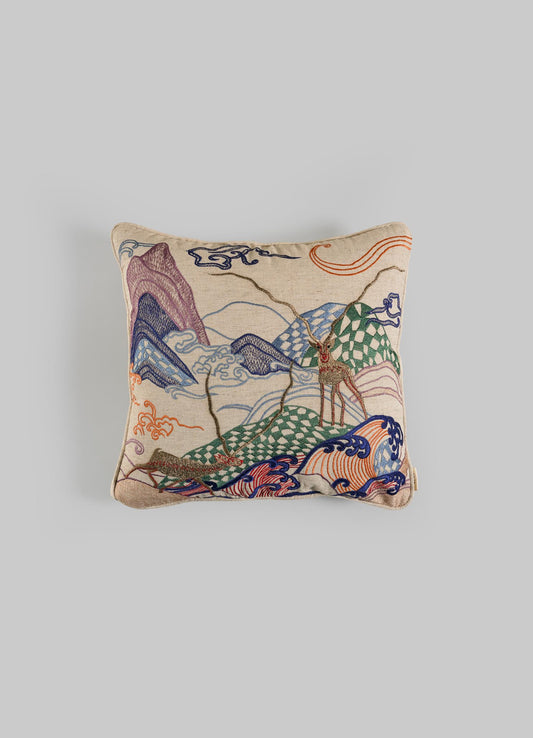 The Viya Dreamscape Blackbuck Multicolour Embroidered Cushion Cover 16"x16" features vibrant mountain, cloud, and deer motifs on beige fabric, inspired by symbolic designs and shown against a light gray background.