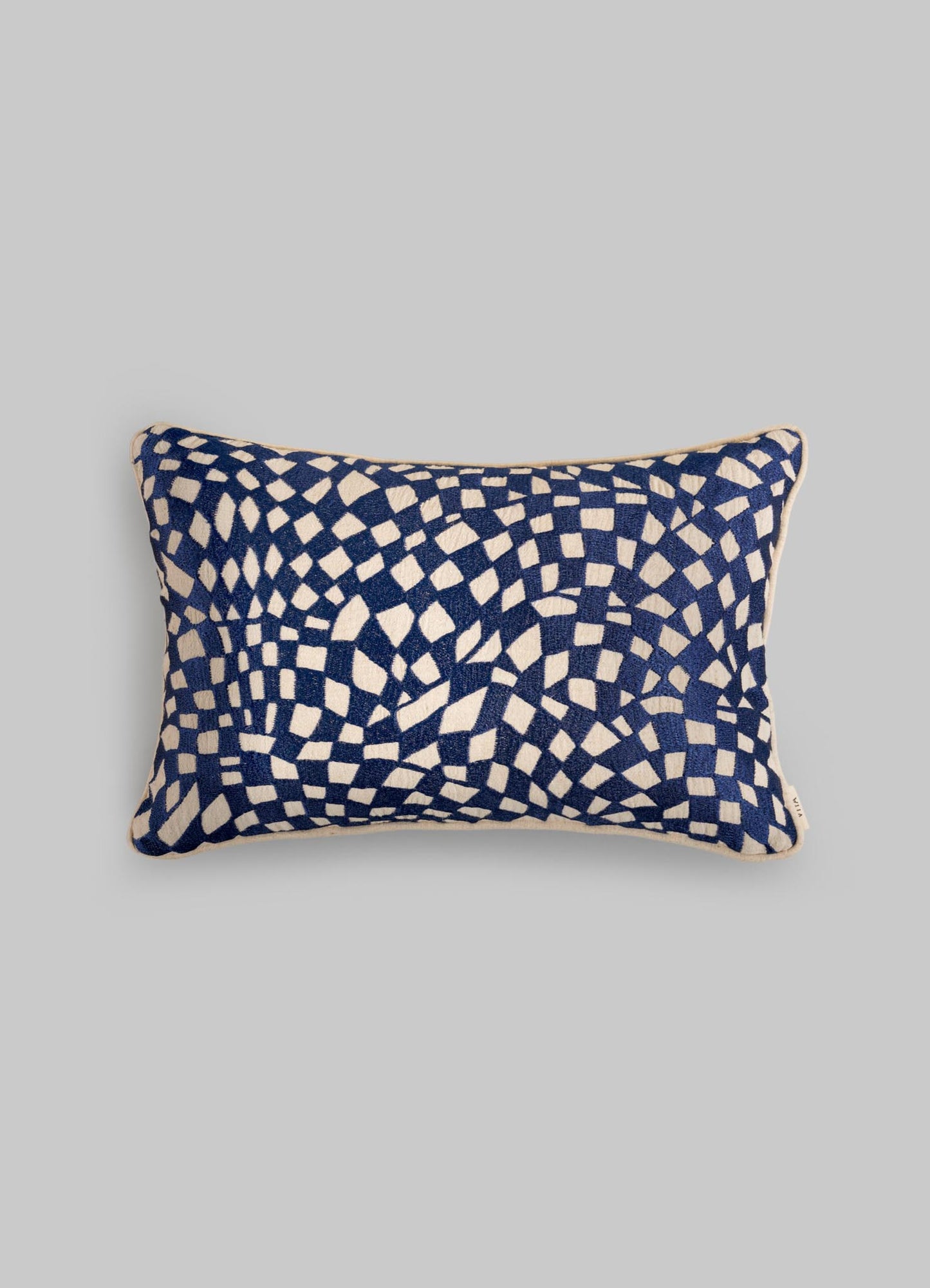 The Viya Dreamscape Blue Embroidered Checks Cushion Cover 12"x18" features navy and white geometric motifs with scattered, curved squares on a plain gray base.