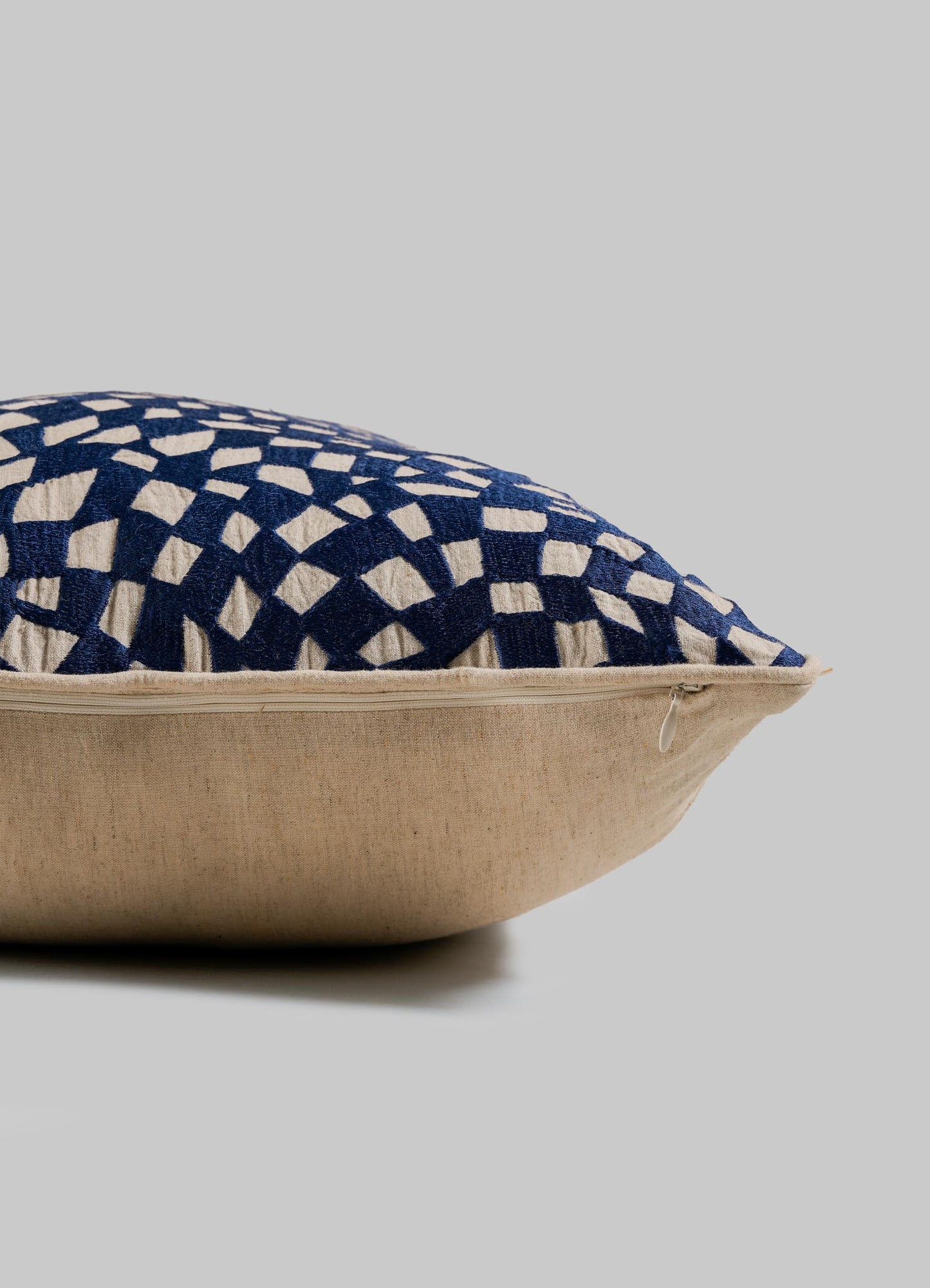 A close-up of the Viya Dreamscape Blue Embroidered Checks Cushion Cover 18"x18", featuring a blue and cream geometric design, visible edge zipper, and set against a plain gray background.