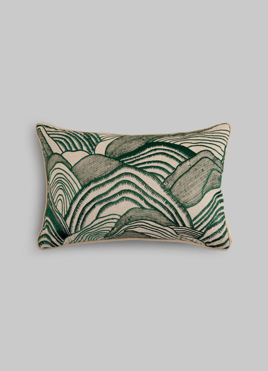 The Viya Dreamscape Green Embroidered Mounds Cushion Cover (12"x18") features abstract, wavy green and beige lines inspired by textile motifs, set against a plain gray background.